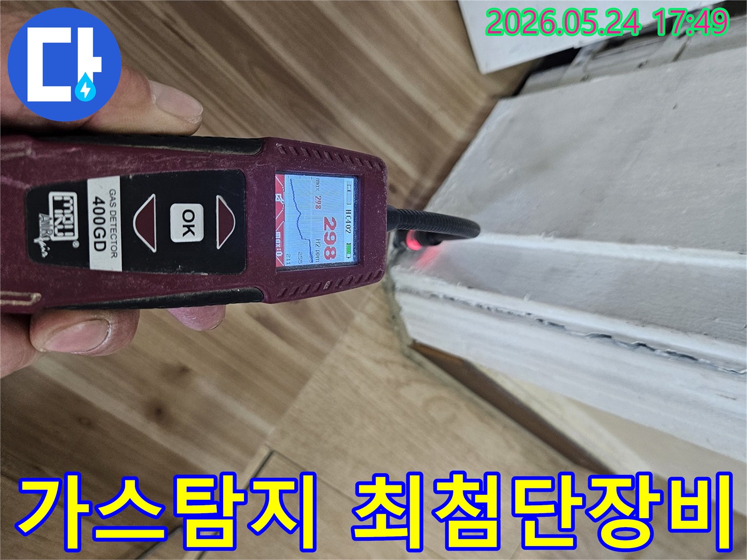 숙련된 누수 엔지니어가 가스 탐지기를 사용하여 벽면 하단에서 누수 반응을 면밀히 확인하고 있습니다.