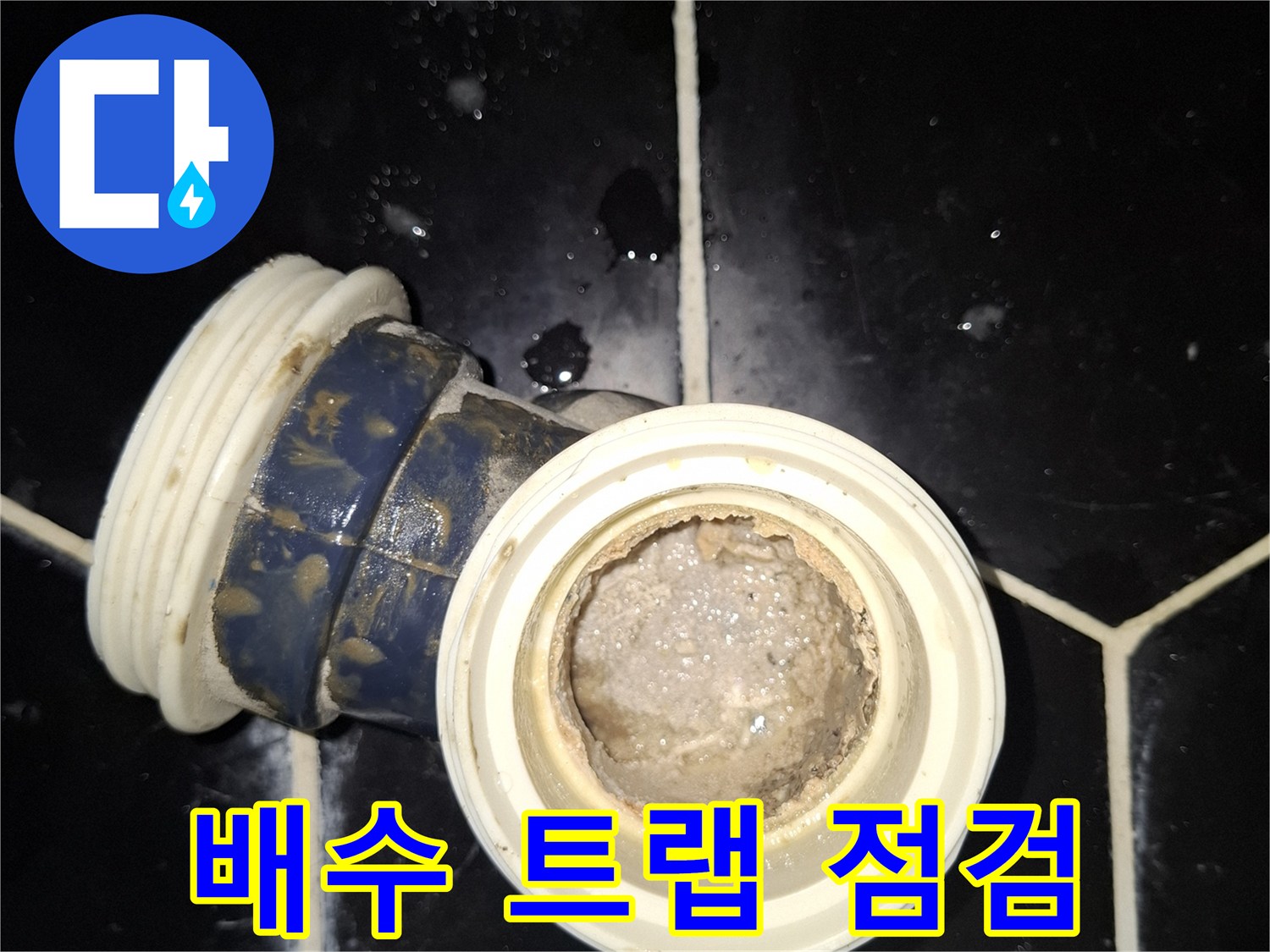 타일 사이에 노출된 배수관 연결 부위의 근접 촬영