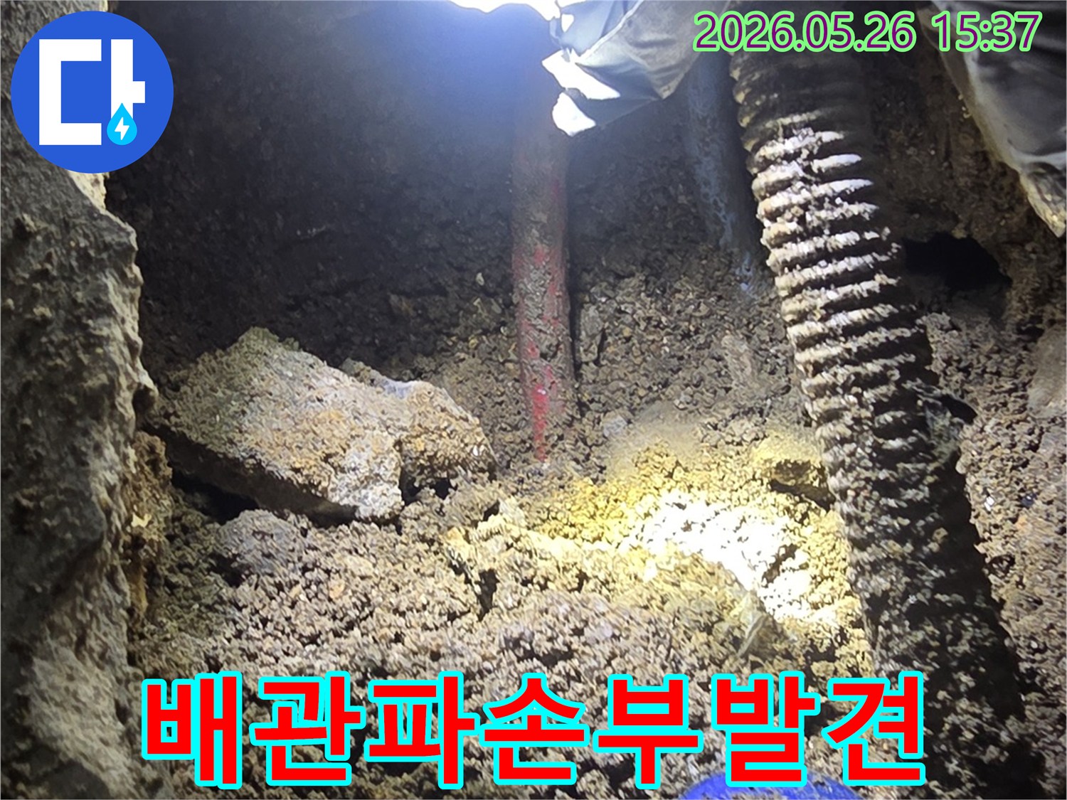 누수-전문가가-어두운-굴착-현장에서-손전등으로-배관-파손-부위를-정밀하게-확인하는-과정