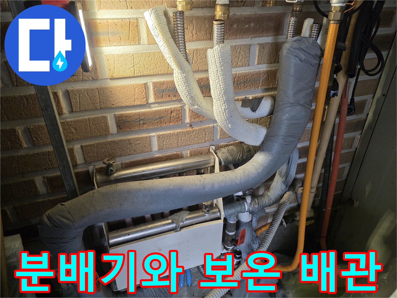 벽돌-벽면에-설치된-보온재-감긴-배관과-분배기