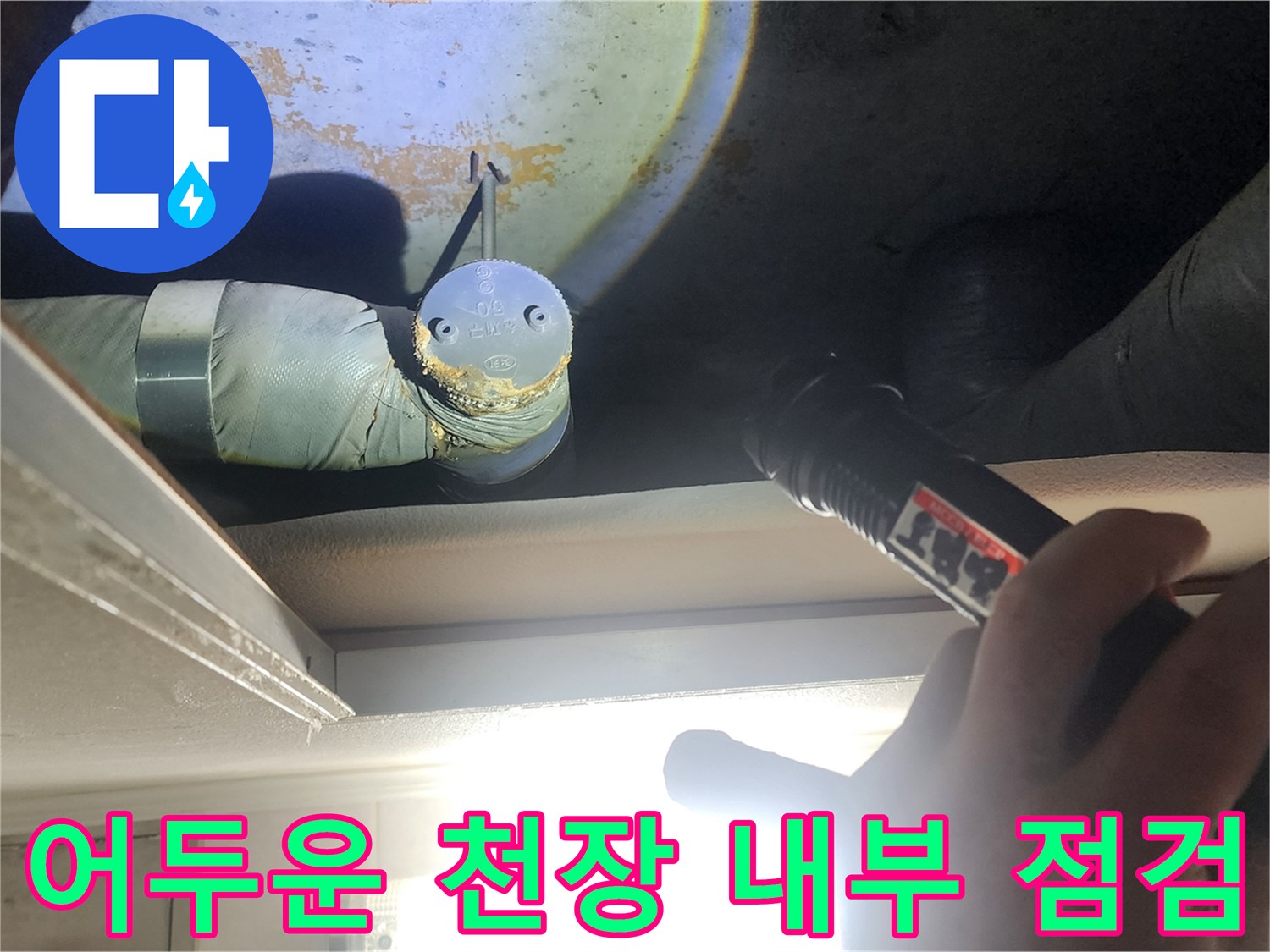 손전등을 사용하여 어두운 천장 속 배관의 누수 흔적을 찾는 모습