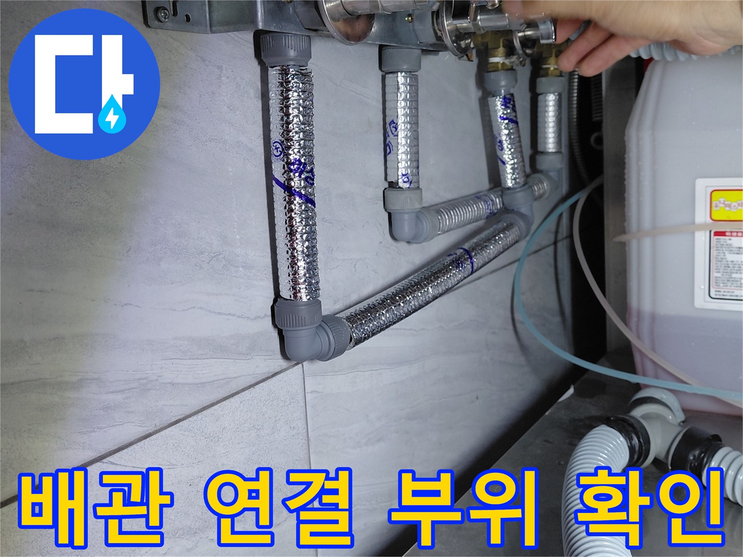 손가락으로 에이콘 배관의 은색 보온재 사이 연결부를 점검하는 장면