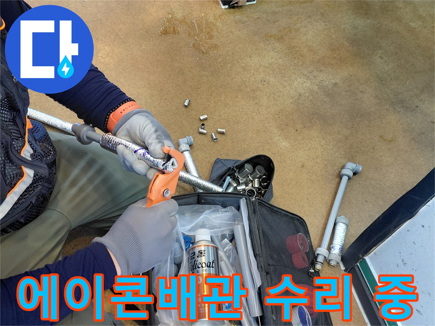주방 하부장 공간에서 에이콘 배관의 연결 부위를 전용 공구로 점검하고 있는 모습