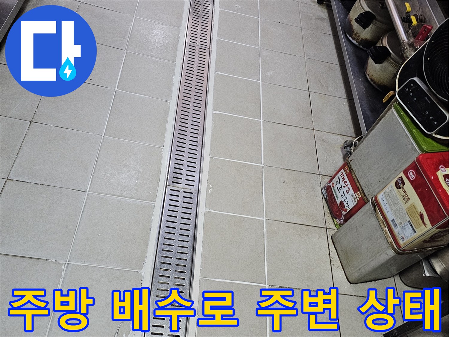 식당 주방 내 스테인리스 배수 트렌치와 타일 경계 부위