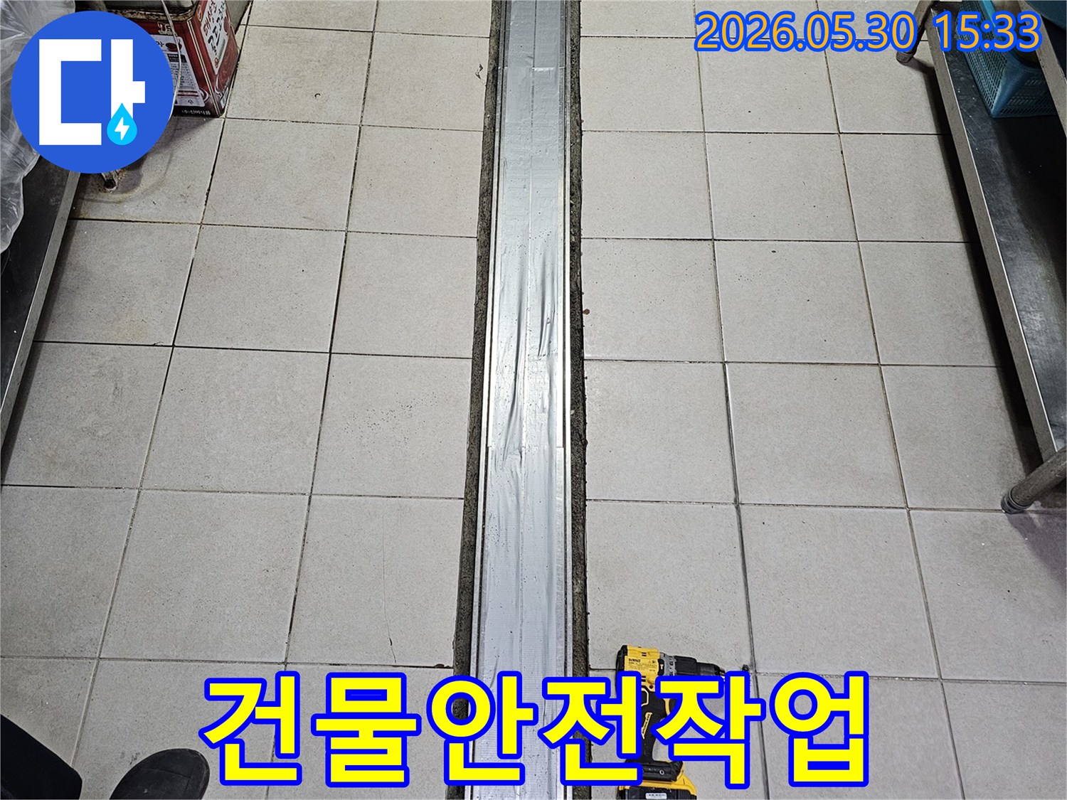 타일 바닥과-배수 트렌치-그리고 작업용 전동 드릴이 놓인-건물 안전을 위한-누수 보수-준비 현장입니다