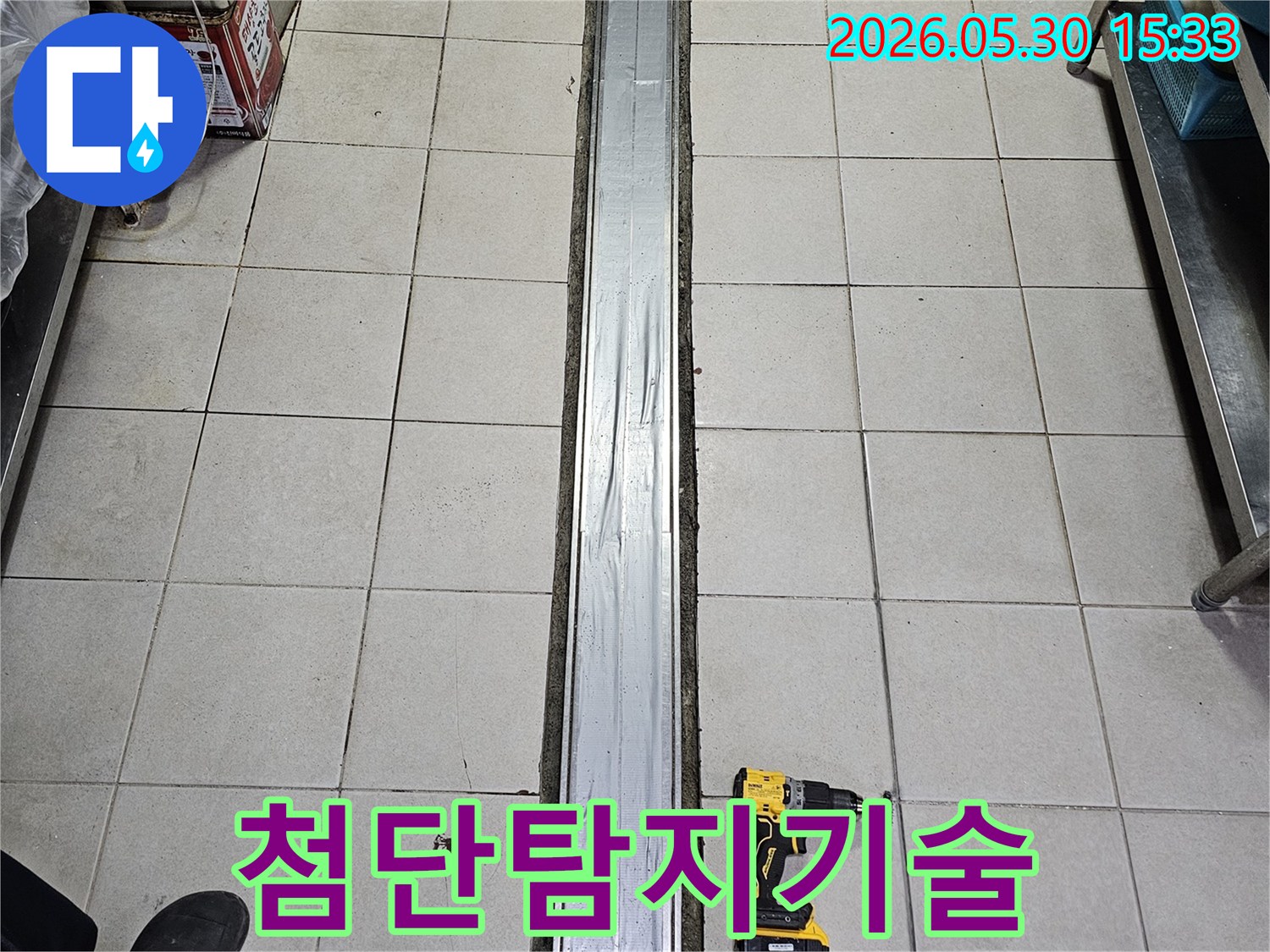타일 바닥과-배수 트렌치-그리고 작업용 전동 드릴이 놓인-첨단 탐지 기술이 적용된-누수 현장입니다