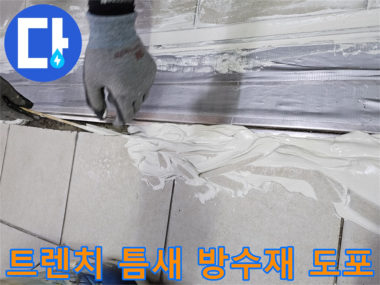 하얀색 백시멘트를-배수 트렌치와 타일 사이의 틈에 채워 넣는 장면