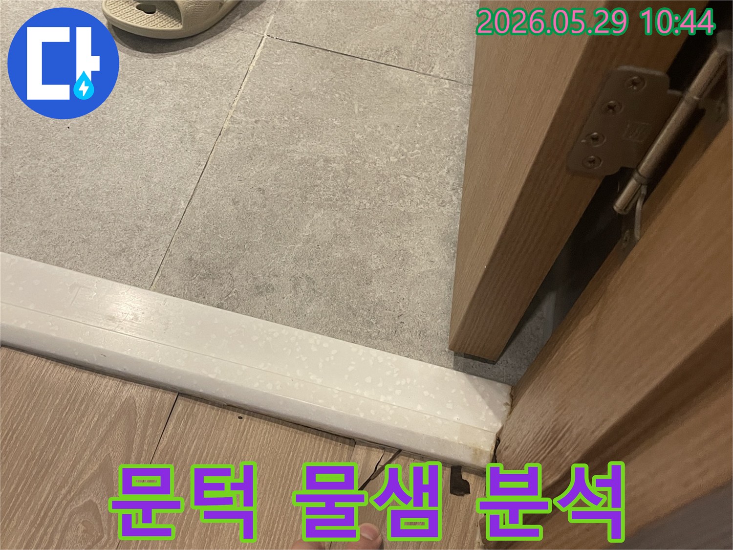 이 사진은 아파트 문턱 주변에서 발생한 물샘 현상을-전문가가 면밀히 분석하는 과정을 담고 있습니다.