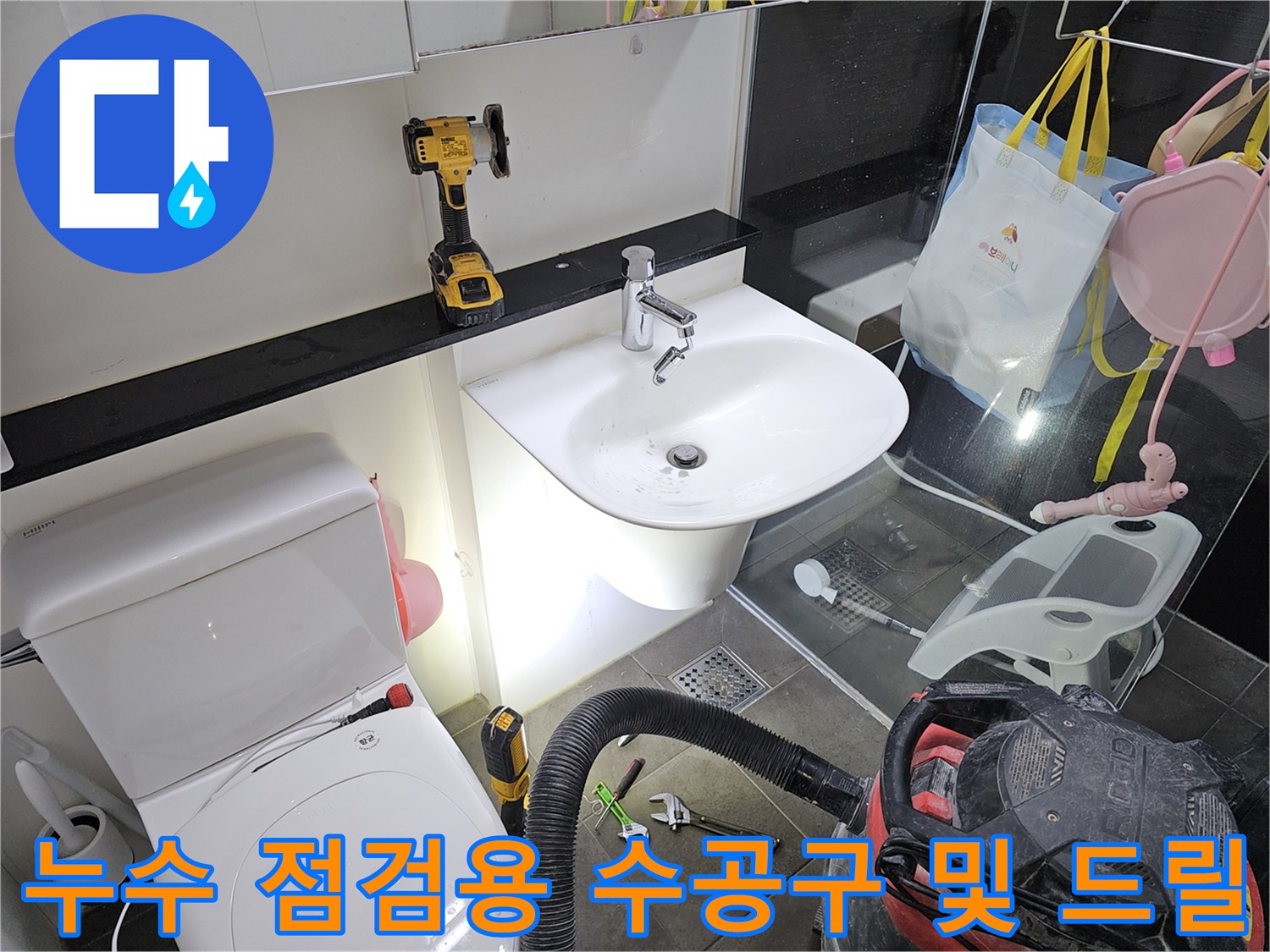 세면대 하부 작업 공간에 놓인 전동 드릴과 렌치