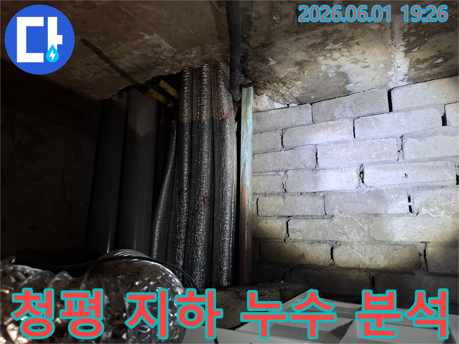 어두운 지하 공간에서-천장 배관과-벽돌 벽면의-누수 흔적을-확인하는 모습의-누수탐지 현장 사진입니다