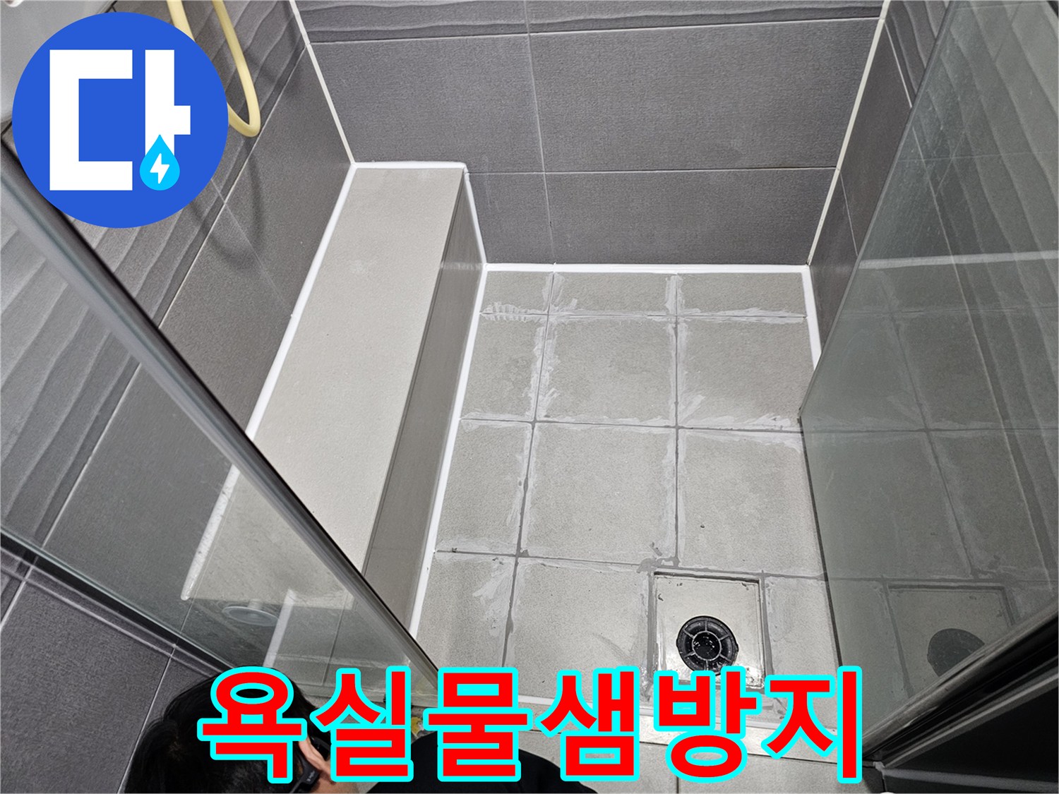 누수 엔지니어가 직접-욕실 바닥의 물샘을 방지하기 위해-타일 줄눈과 경계면을 새로운 실리콘으로 마감하는 작업입니다.