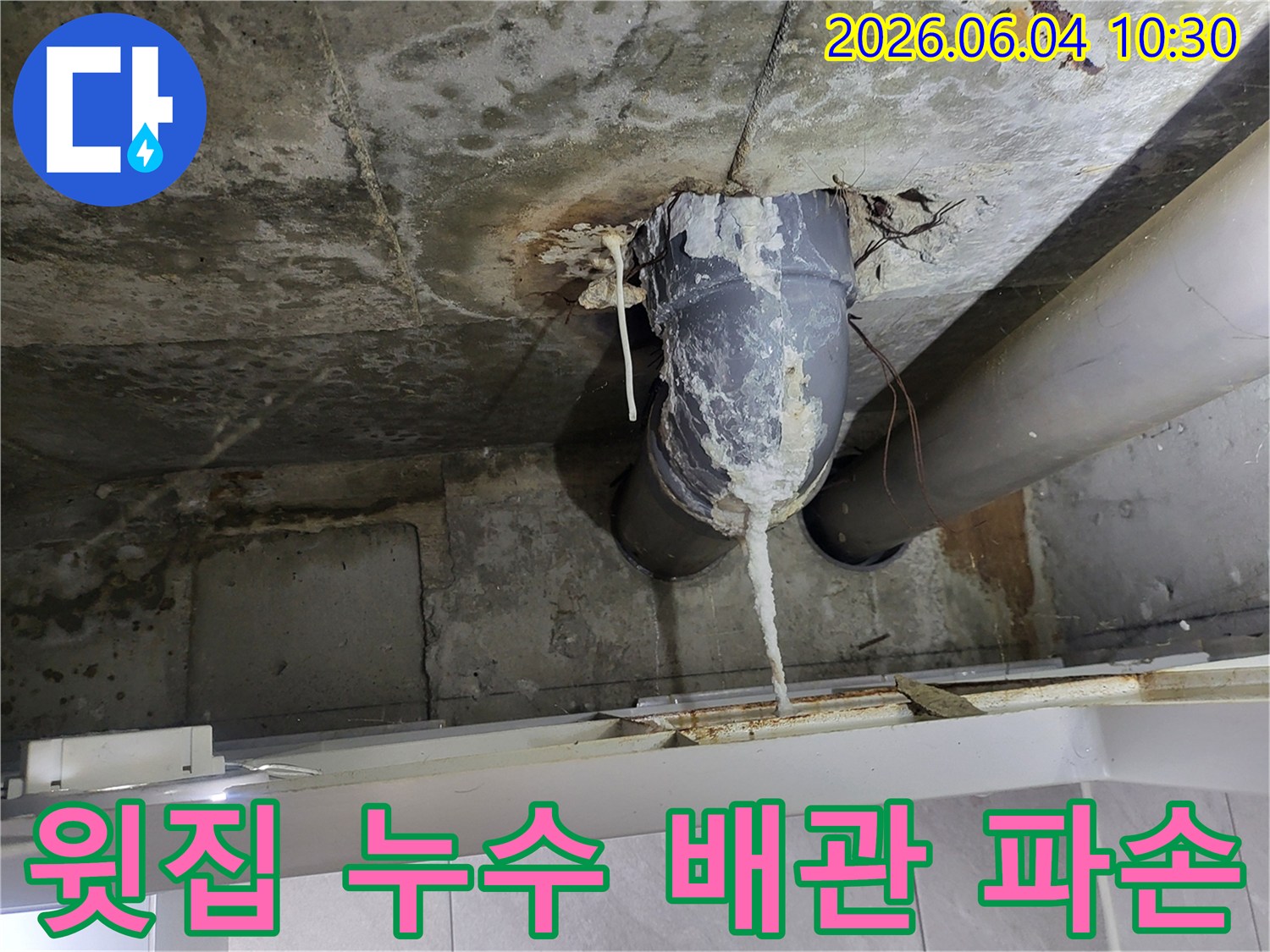 천장 콘크리트 사이로 보이는 배관에서-하얀 석회질 침전물이 길게 늘어진 모습