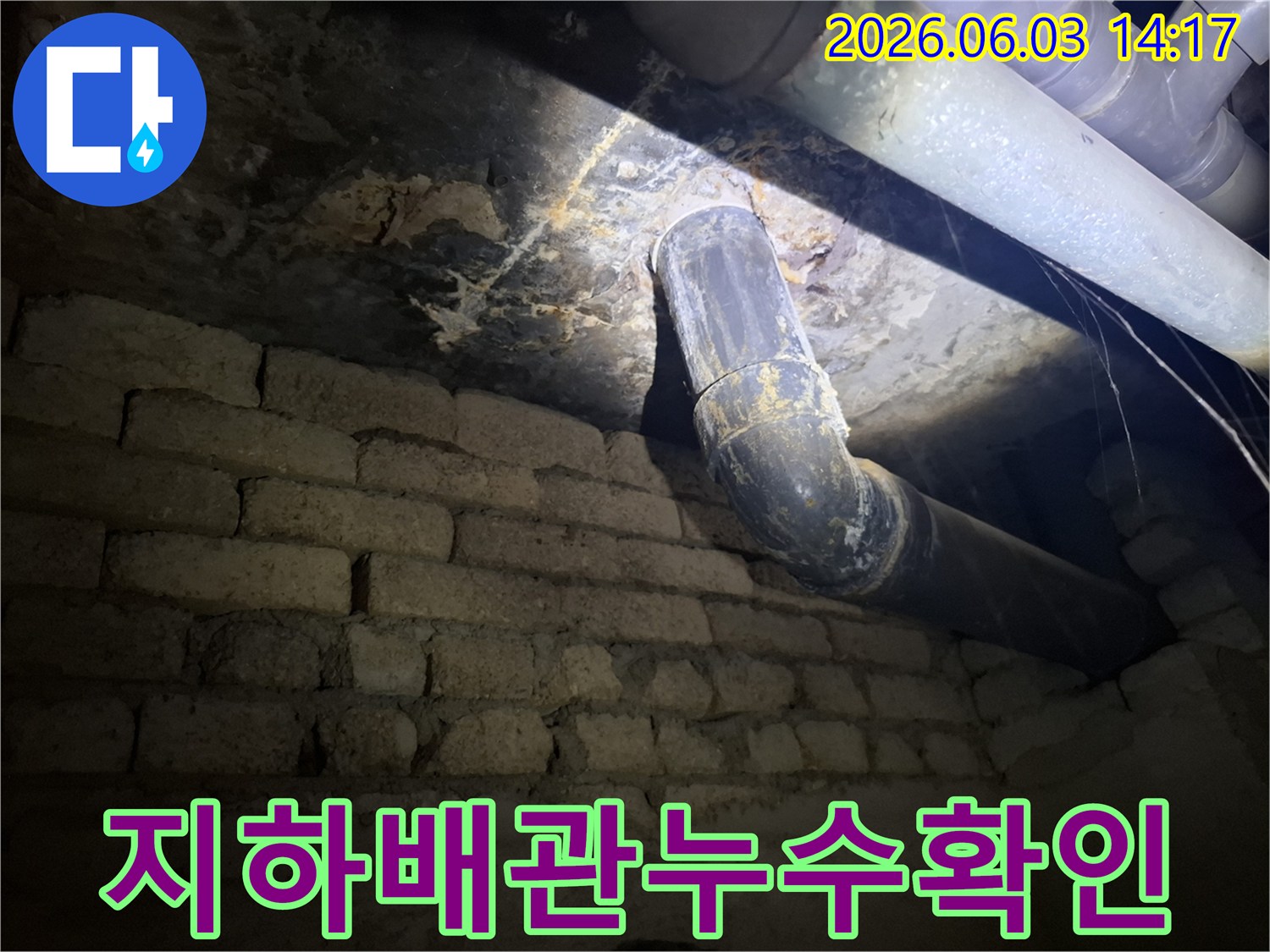 어두운 지하 공간에서-낡은 배관과-벽돌 벽에 발생한-누수 흔적을-조명으로 비춰-정밀하게 검사하는 모습