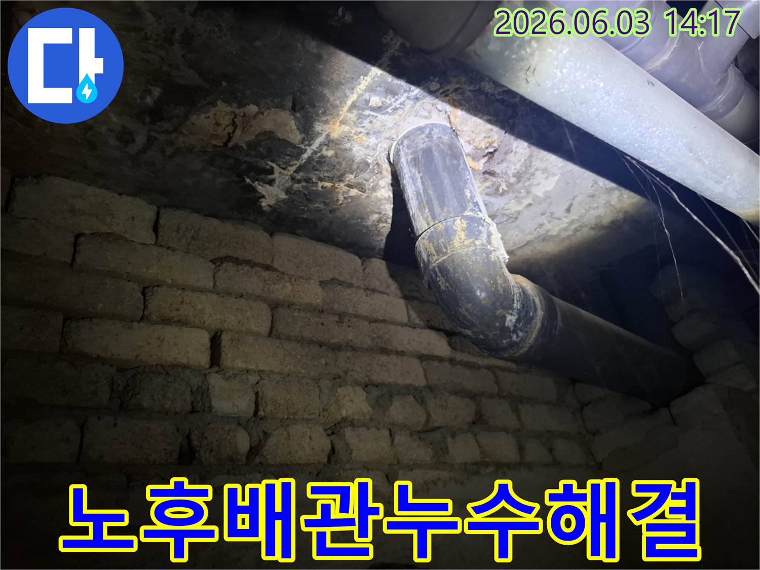 어두운 지하 공간의-낡은 벽돌 벽과-오래된 배관 주변에서-발견된 누수 흔적을-조명으로 비추어-정밀하게 진단하는 모습