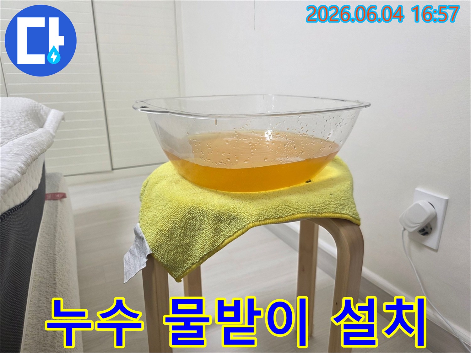 천장에서 물이 떨어지는 긴급 상황에서-바닥 손상을 막기 위해-설치된 임시 물받이와-노란 수건의 모습
