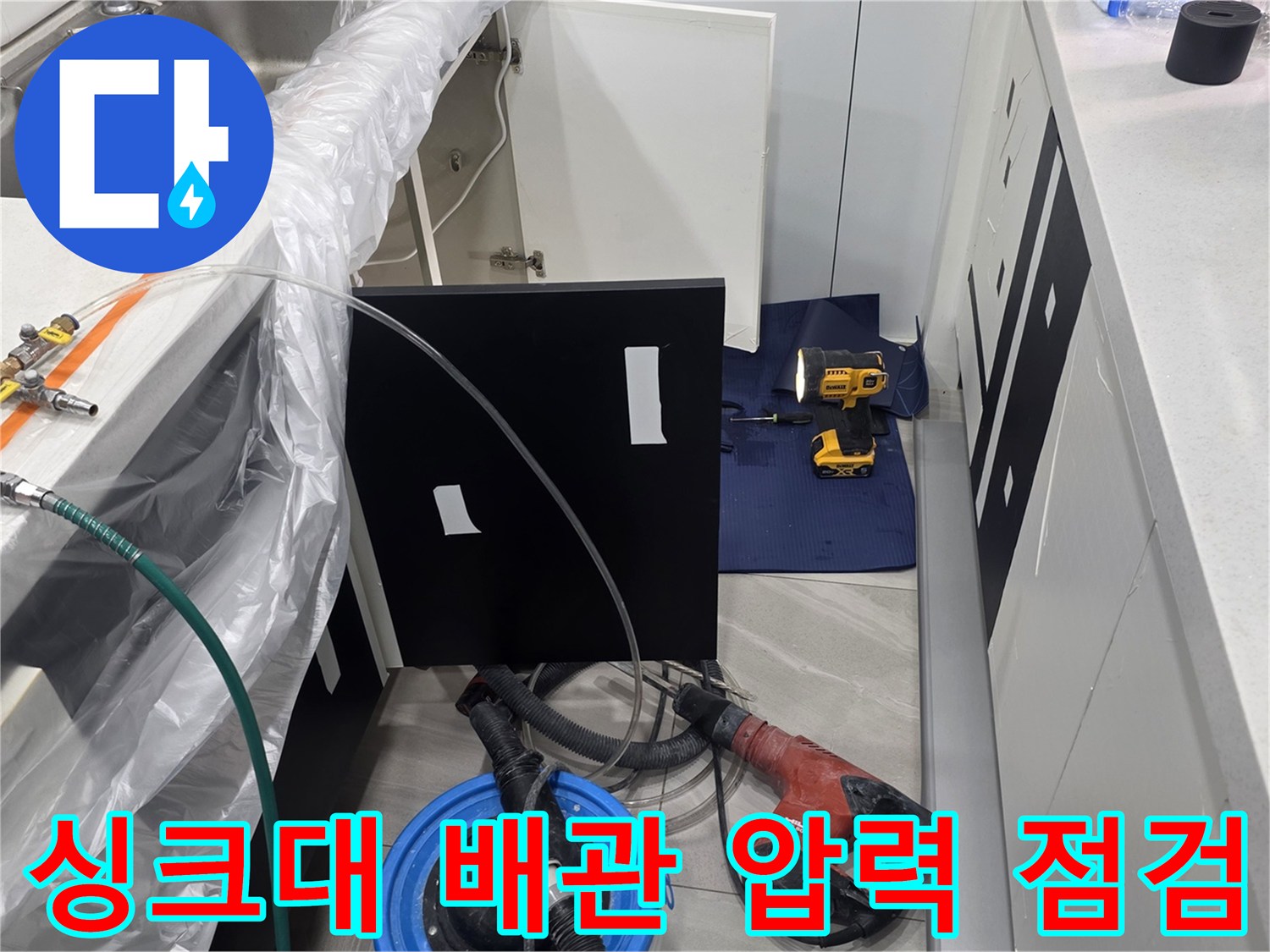 배관 누수 탐지를 위해 싱크대 아래에 압력계를 설치하여 검사하는 모습입니다.