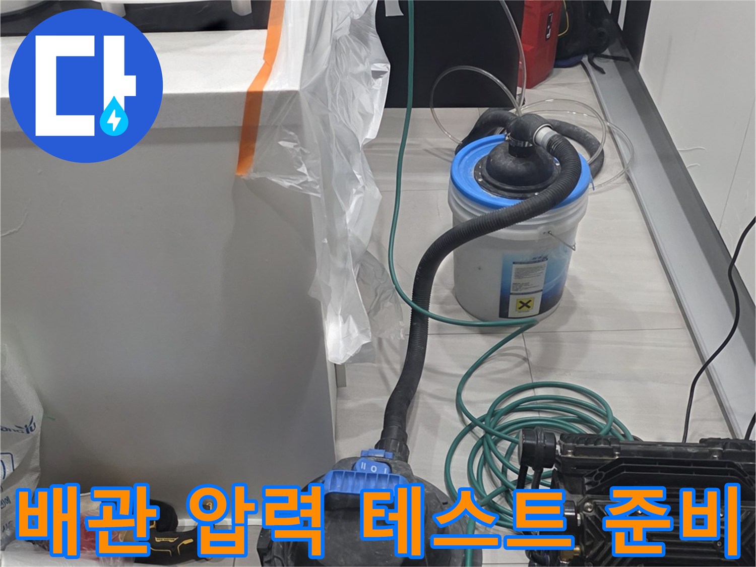 싱크대 하부장 근처에 설치된 배관 공압 테스트용 장비와 호스들