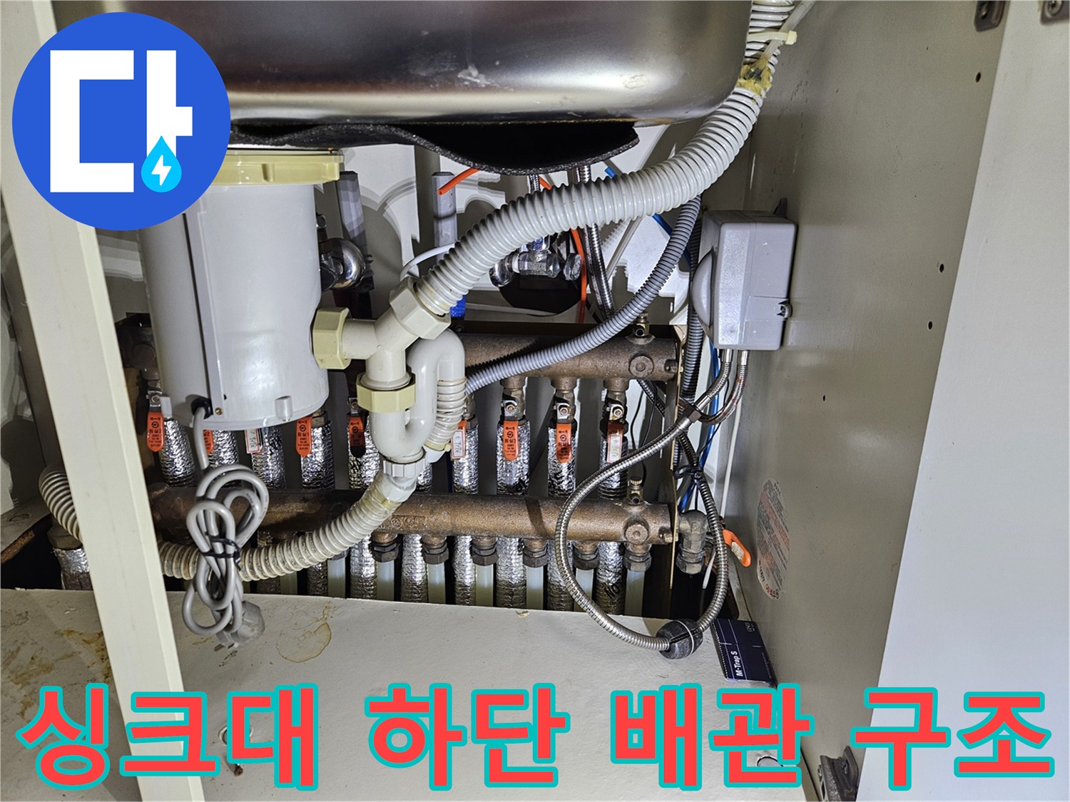 싱크대 아래 공간-복잡한 난방 분배기와 연결 배관들의 모습
