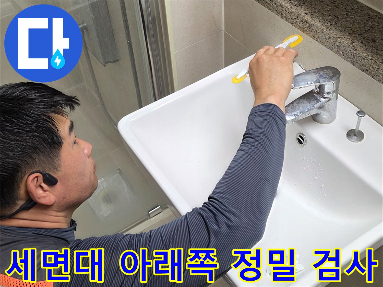 세면대 하단 배관 부위를 손으로 만져보며 점검하는 작업자