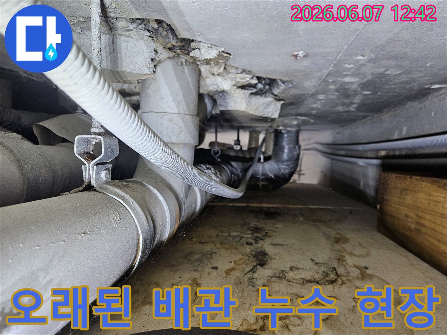 오래된 배관에서 물이 새어 나와-주변 콘크리트와 바닥에-심각한 물자국을 남긴-누수 현장의 모습입니다.