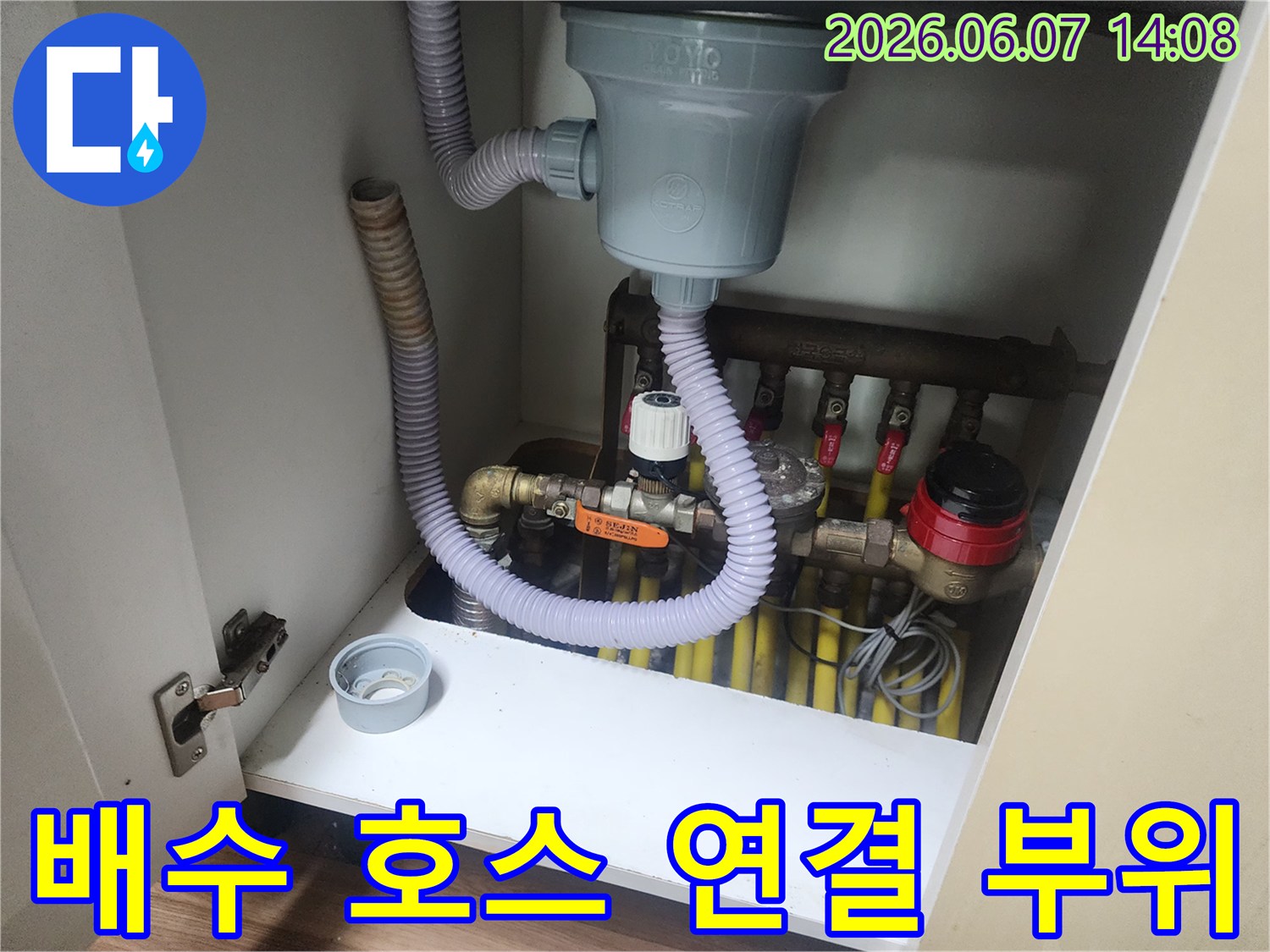 싱크대 하부장 내부의 굵은 배수관과 분기된 급수 라인 상세 사진입니다.