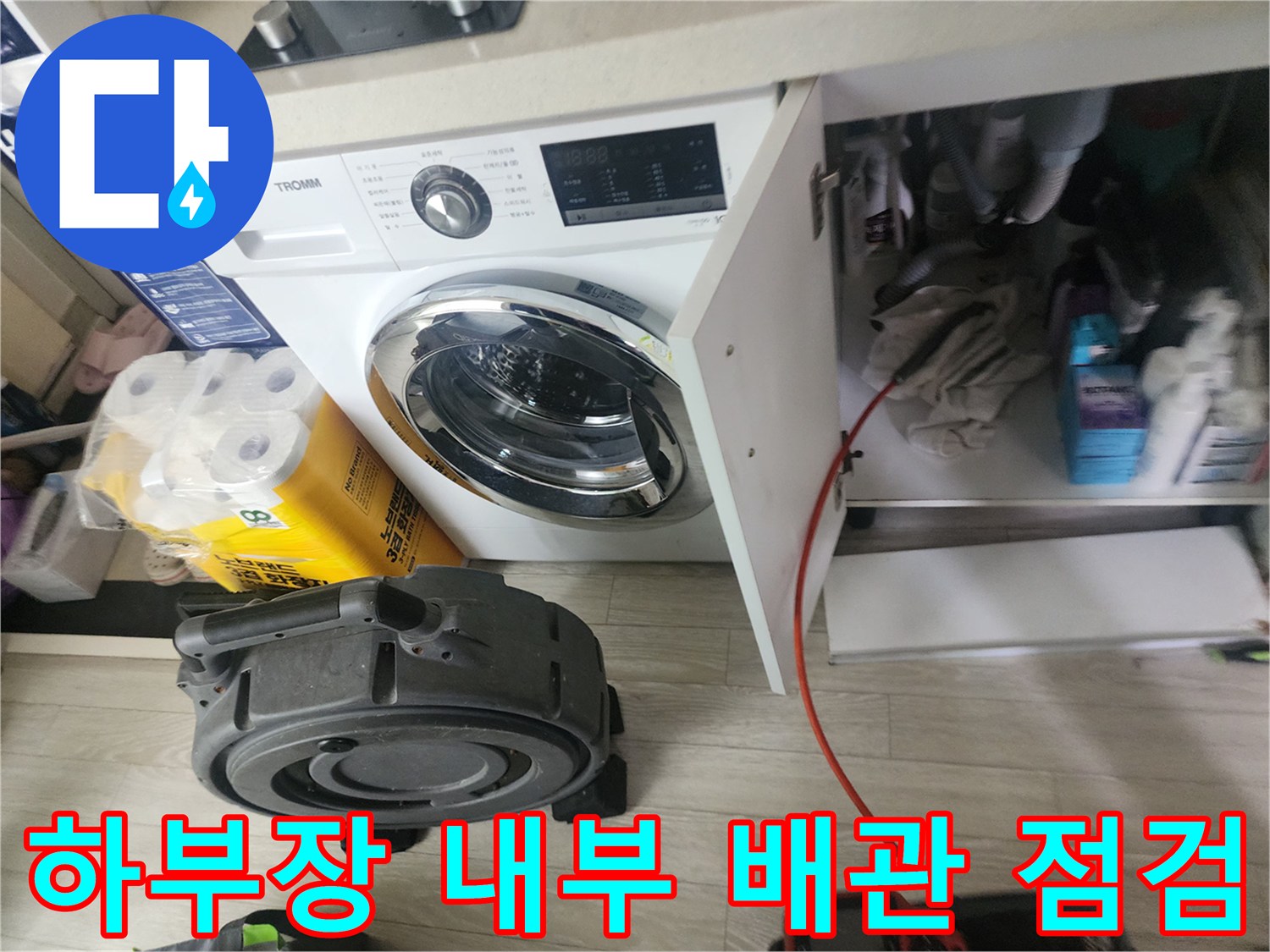싱크대 하부장 내부에 배치된 배관 점검용 장비와 주변 환경