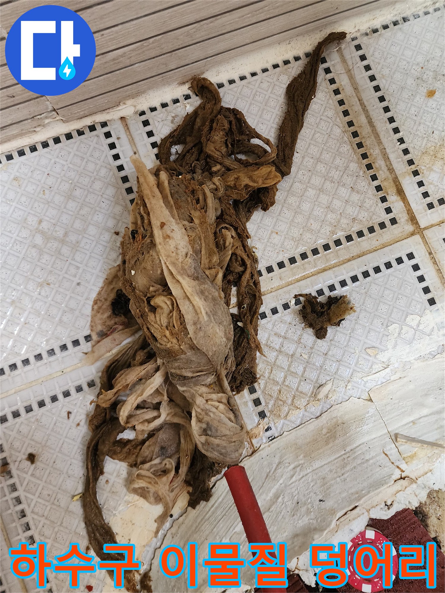 화장실 바닥 타일 위에 놓인 거대한 머리카락과 섬유 슬러지 뭉치