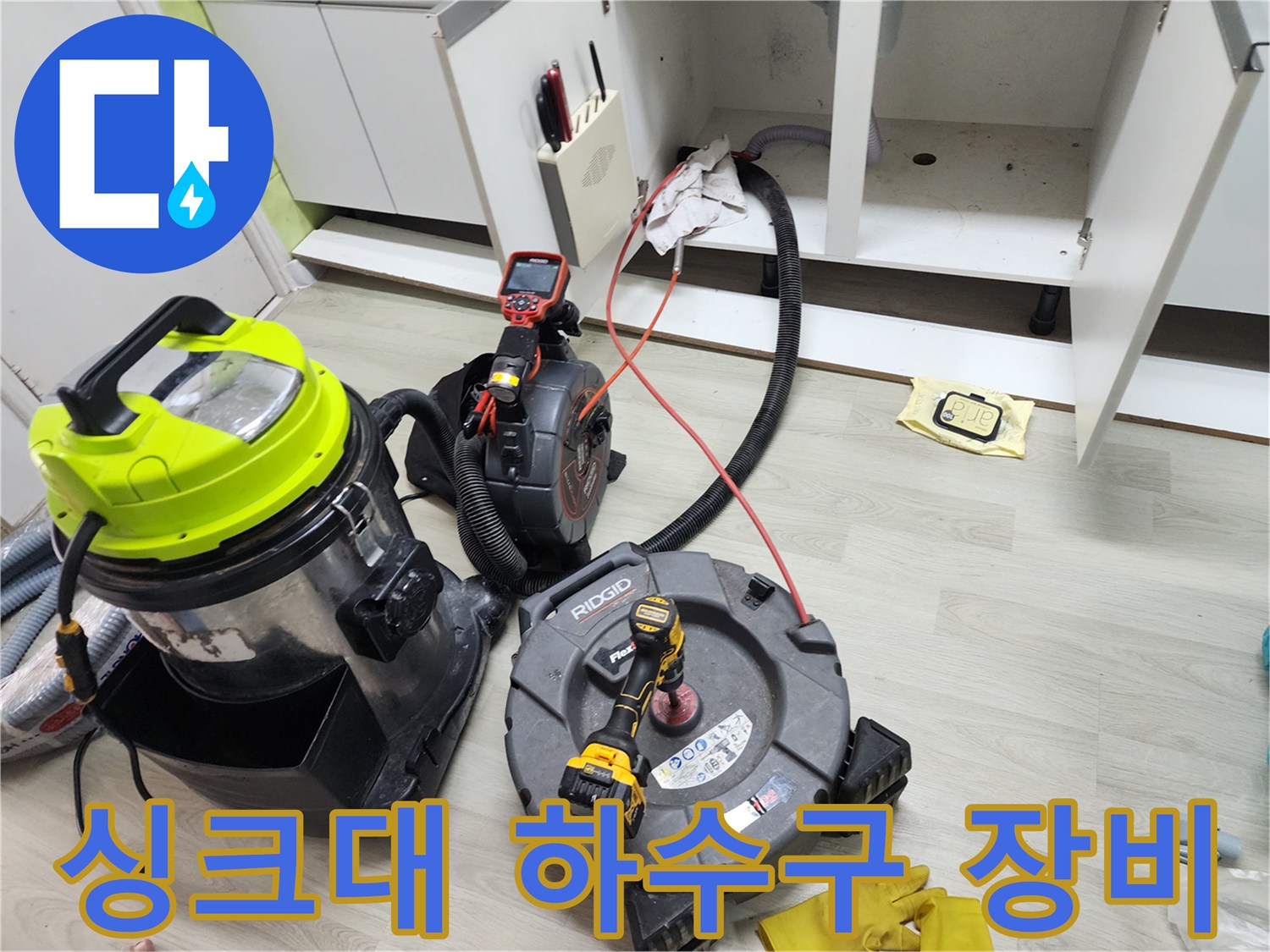 주방 싱크대 하부장 아래 배치된 배관 스케일링 및 석션 장비 세트