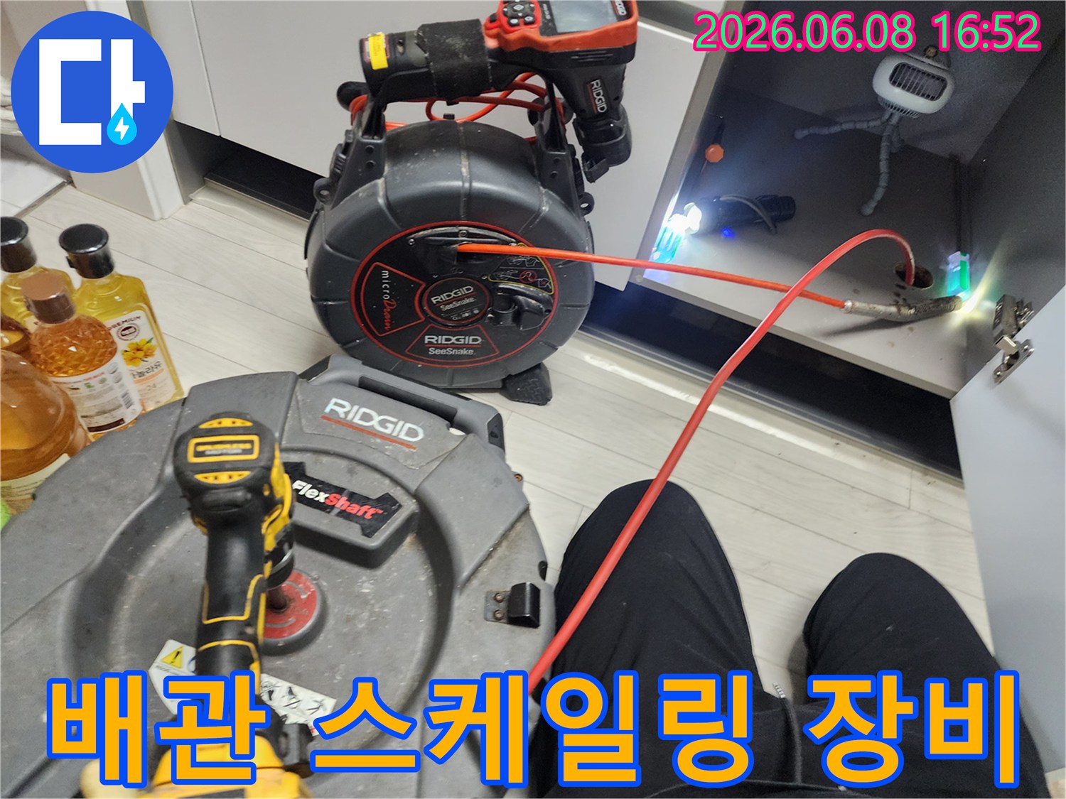 싱크대 하부장 내부에서 작업 중인 배관 스케일링 장비와 케이블