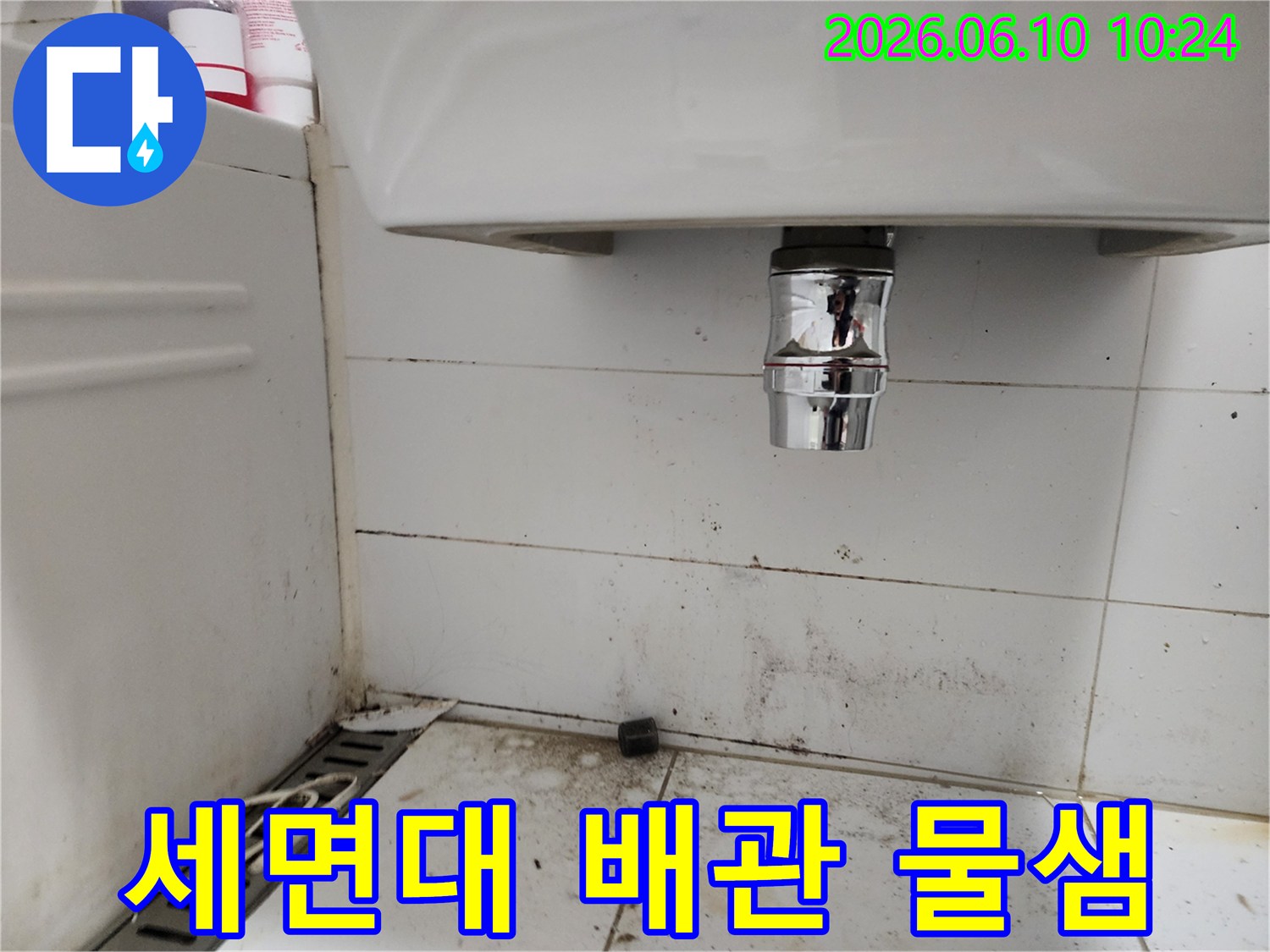 욕실 세면대 아래 배관에서 발생한 물샘으로 인한 바닥 오염-전문가가 확인 중인 모습