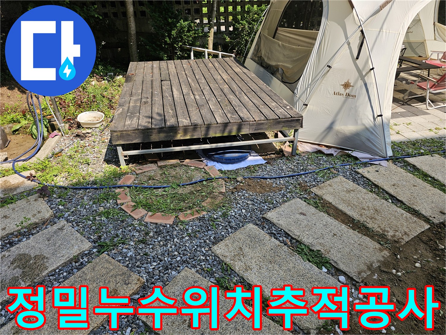 마당 내 데크 하부와 연결된 배관들의 누수 여부를 탐지기로 점검하는 장면