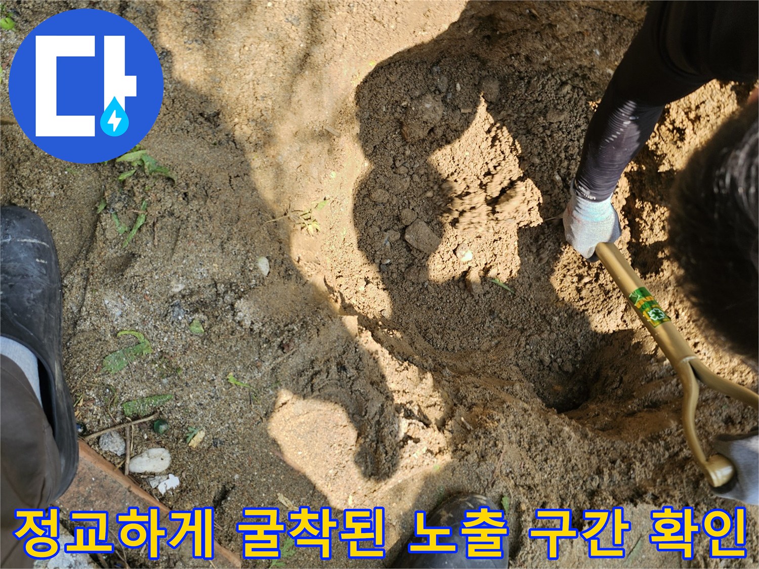 작업자가 삽으로 배관 주변 토사를 제거하며 수리 지점을 특정하는 장면