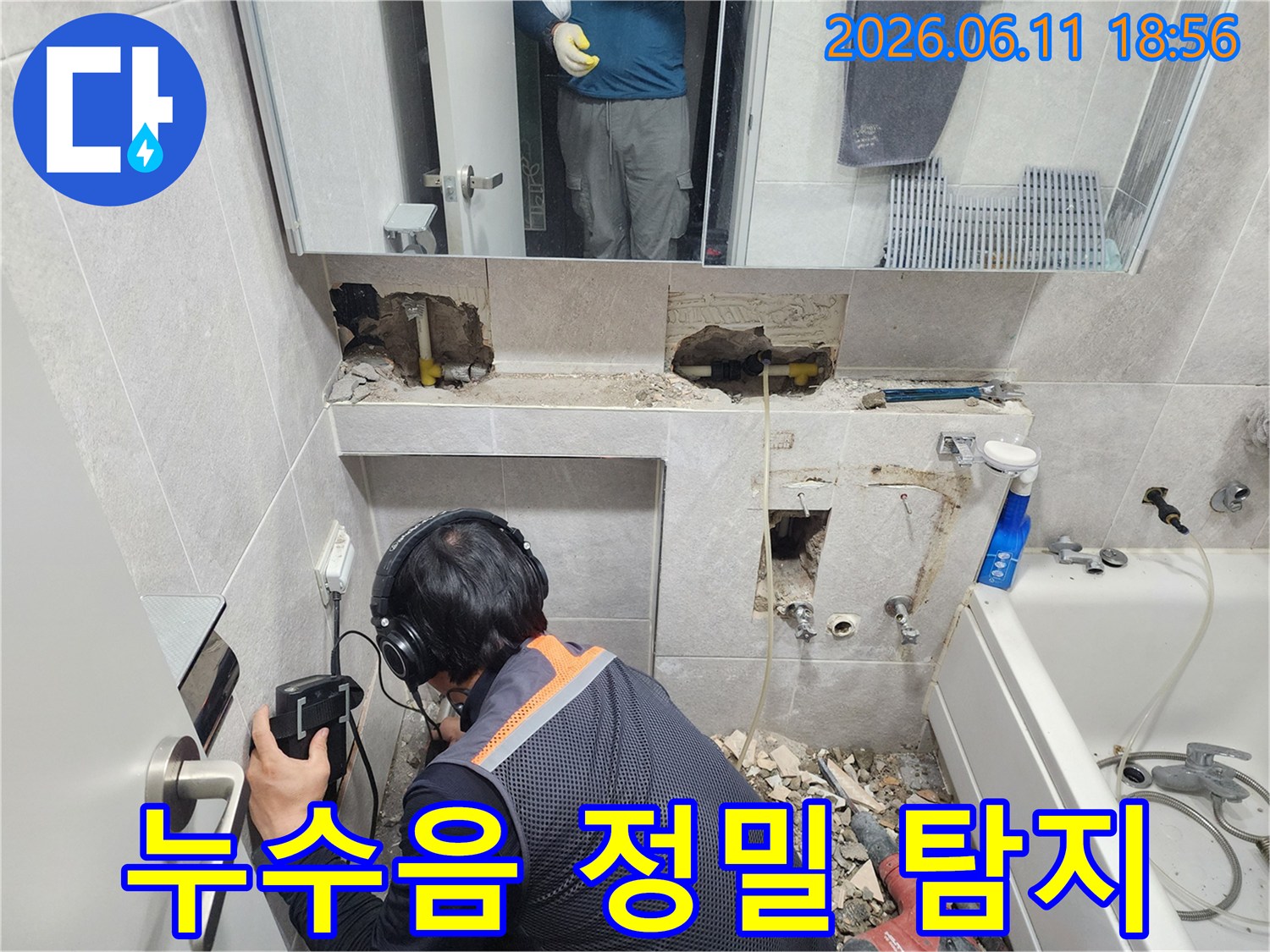 숙련된 누수 전문가가-헤드폰과 탐지 장비로-욕실 내부의 누수음을-세밀하게 분석하는 장면