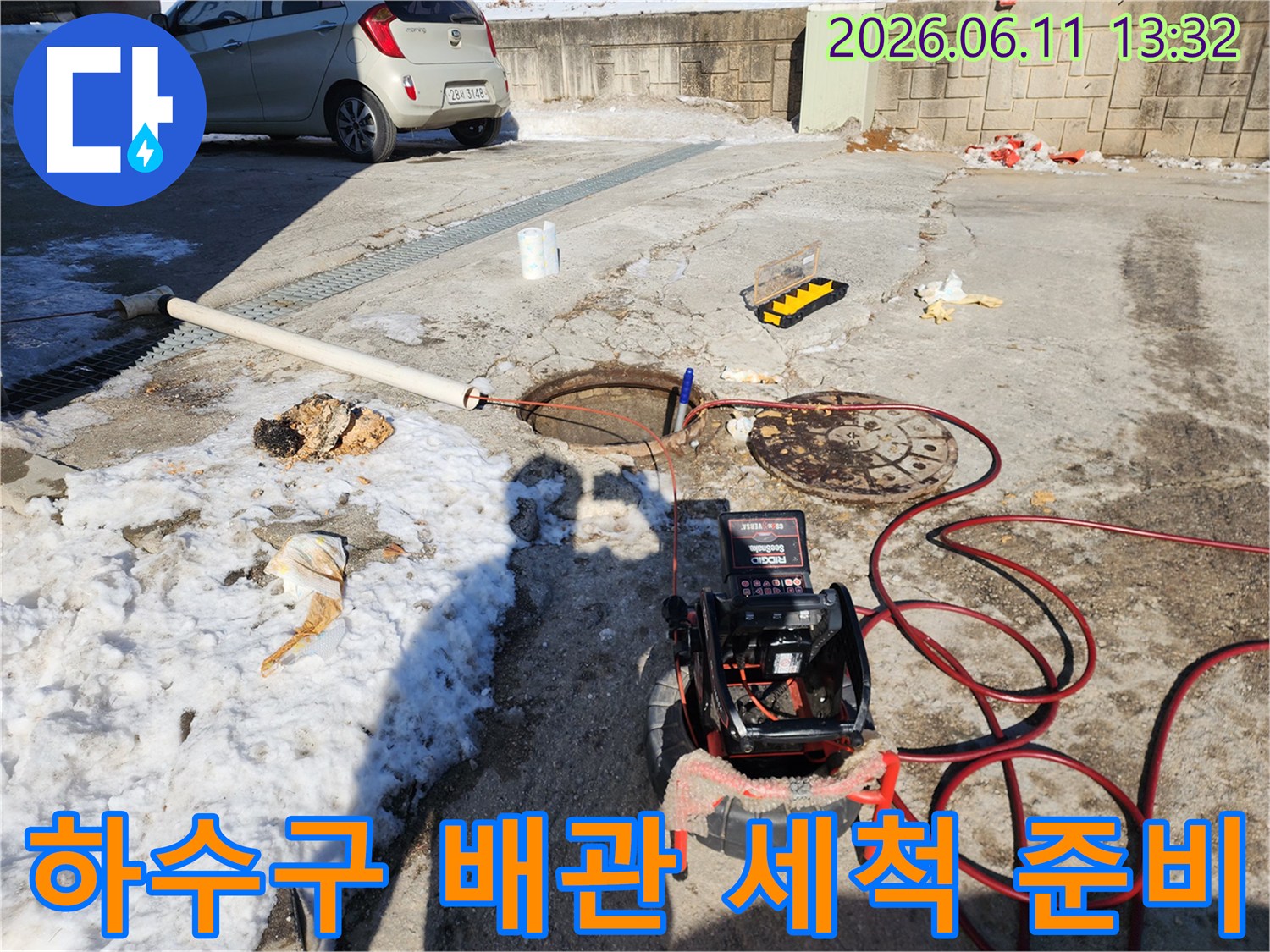 맨홀 뚜껑과-고압 세호스가 놓인 하수구 작업 현장 사진