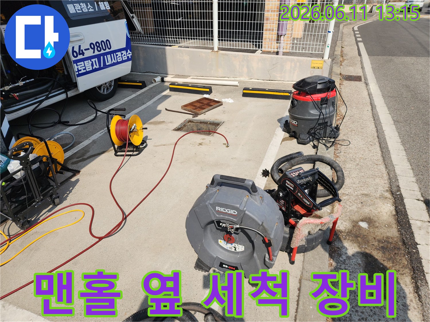 맨홀 작업 현장에 놓인 노란색 호스 릴과 리지드 고압 세척기