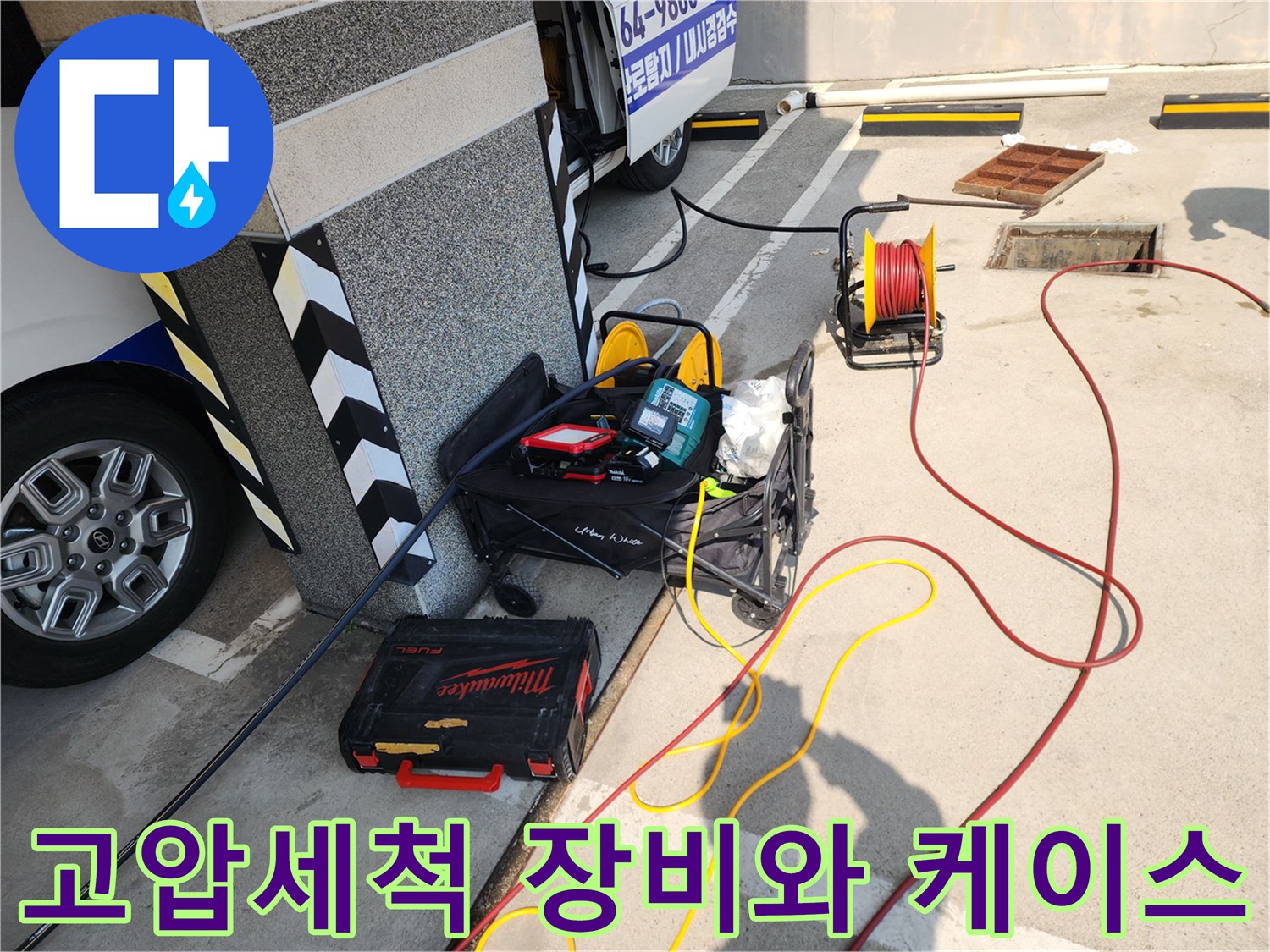 현장 바닥에 놓인 전문 배관 청소용 호스 릴과 밀워크 공구함 세트