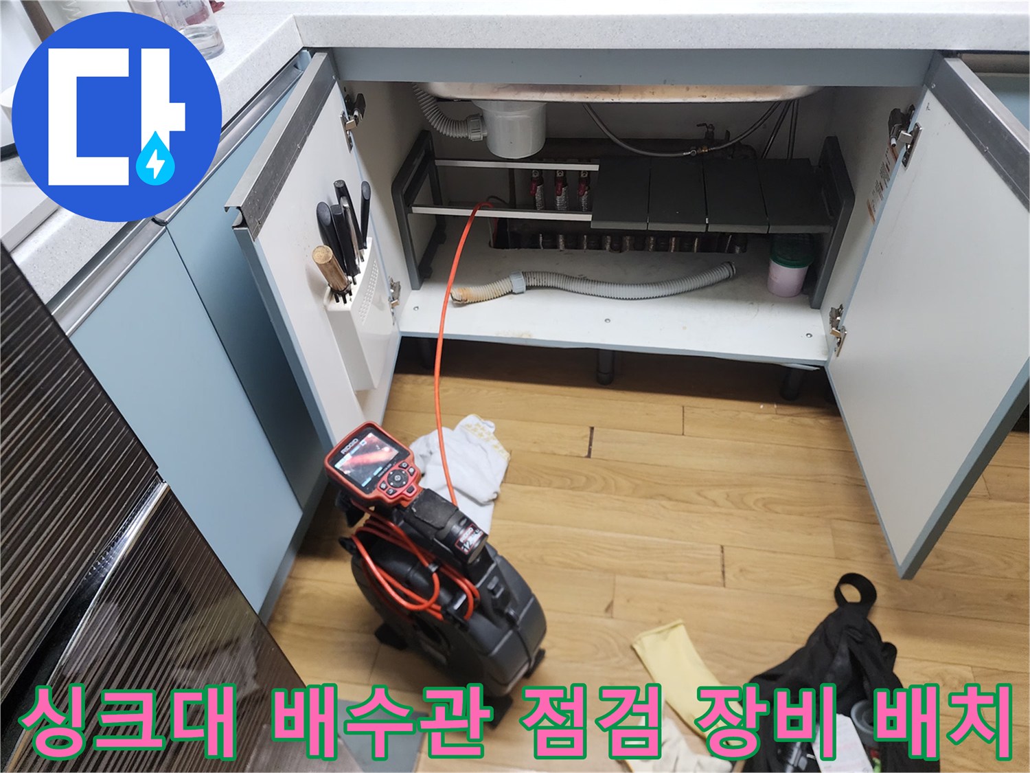 싱크대 아래쪽 배수 호스 주변에 놓인 작업용 내시경 카메라와 석션기