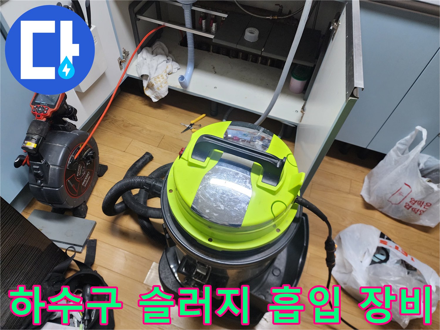 싱크대 하부장 내부의 배관 이물질을 제거하기 위해 배치된 전문 석션 장비와 호스입니다.