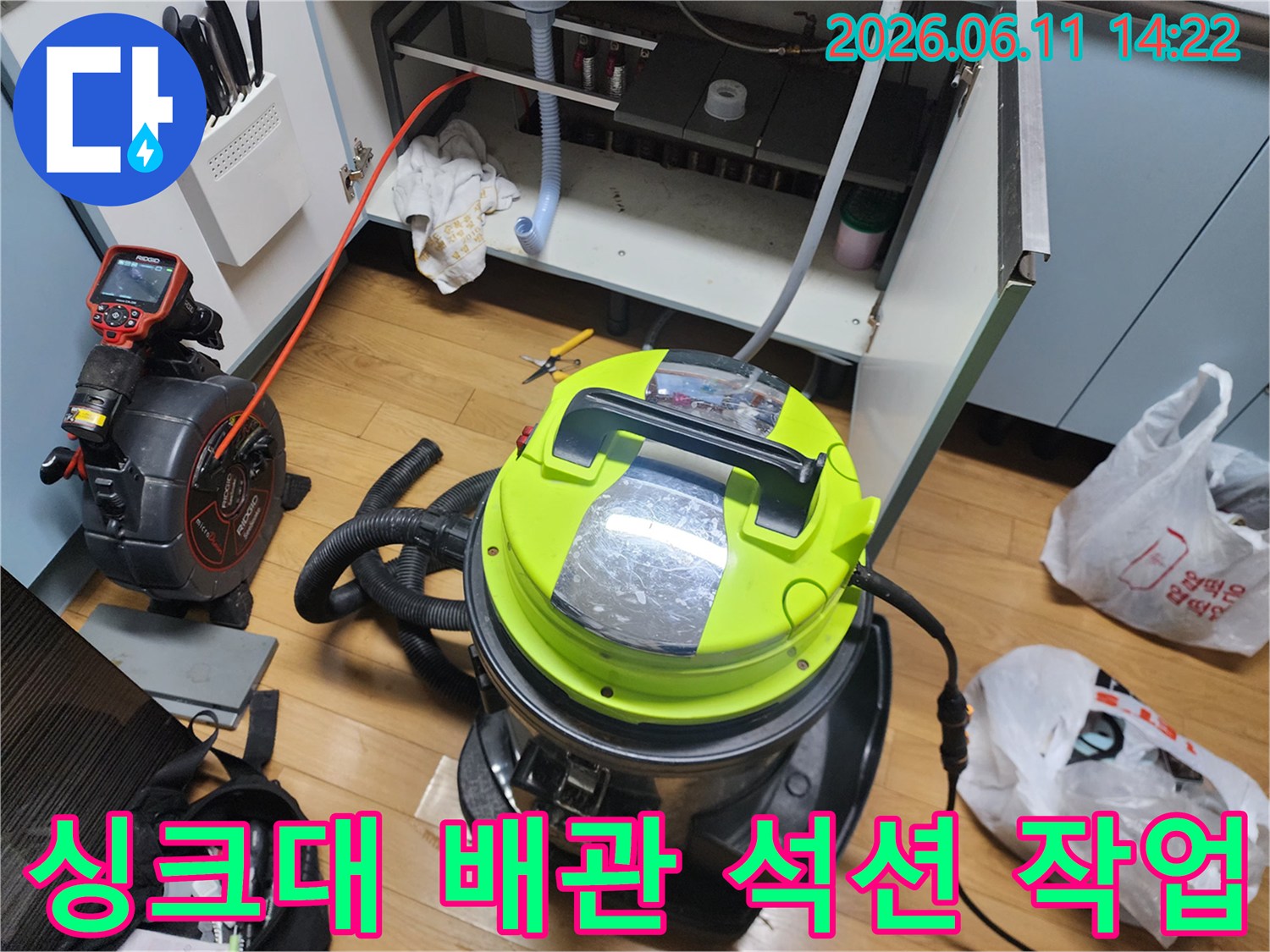 싱크대 하부장 아래에서 진행 중인 배관 이물질 제거용 석션 장비입니다.
