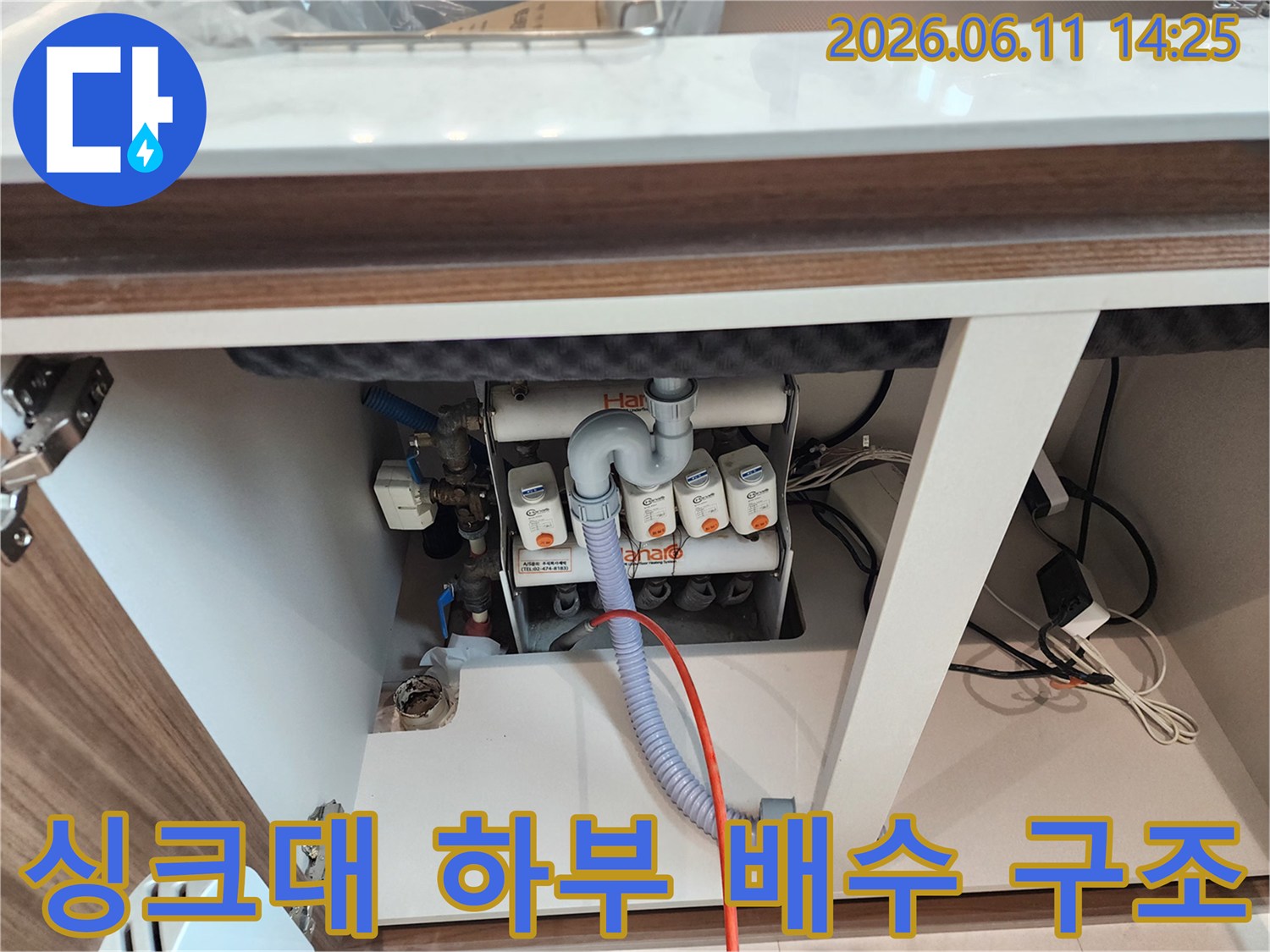 싱크대 아래쪽의 흰색 배수 분기 장치와 연결된 호스들