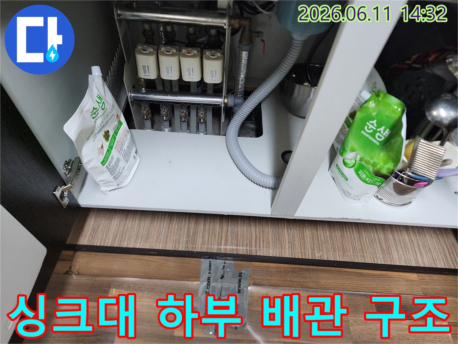 정수 필터와 싱크대 하부 배수 호스가 연결된 내부 모습입니다.