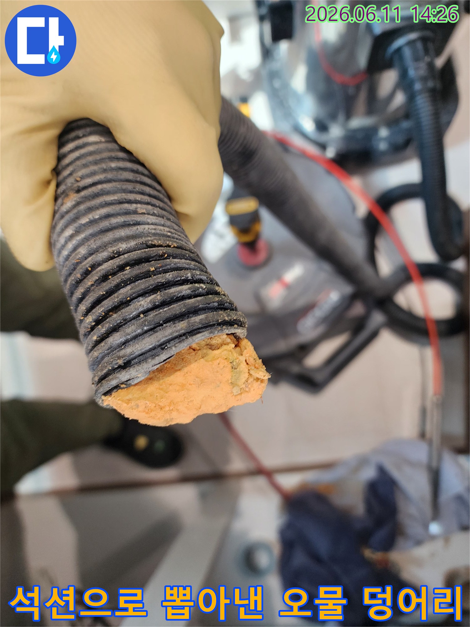 주름진 검은 호스 끝에 뭉쳐 있는 커다란 기름 슬러지 덩어리
