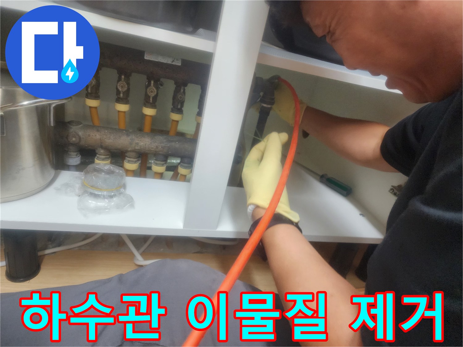 장갑을 낀 작업자가 배관 내부의 슬러지를 제거하기 위해 장비를 조작하고 있습니다.