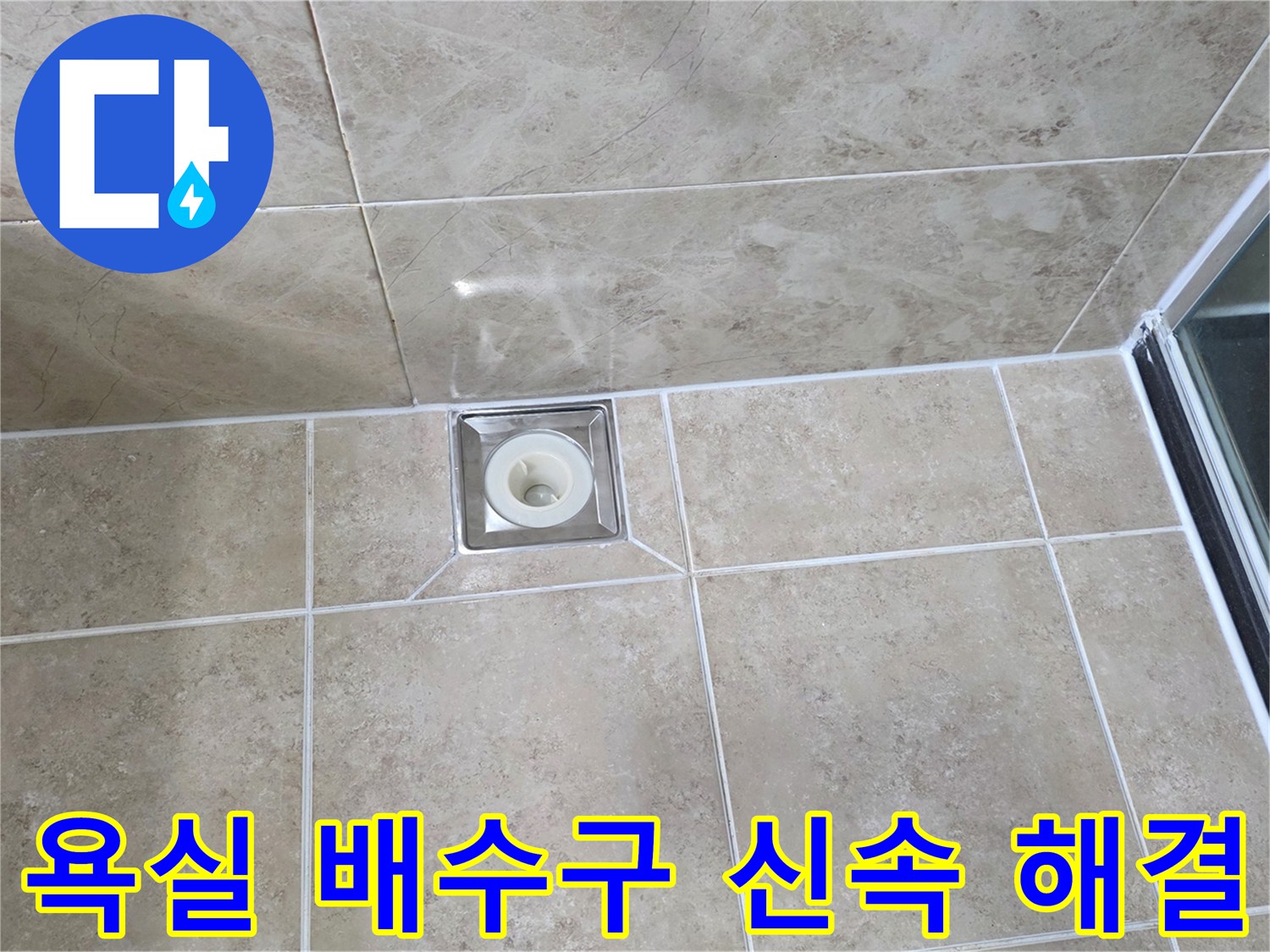 깨끗하게 시공된 욕실 타일 중앙에-사각형 배수구가 위치하며-주변 마감 상태를 면밀히 관찰하는 사진입니다