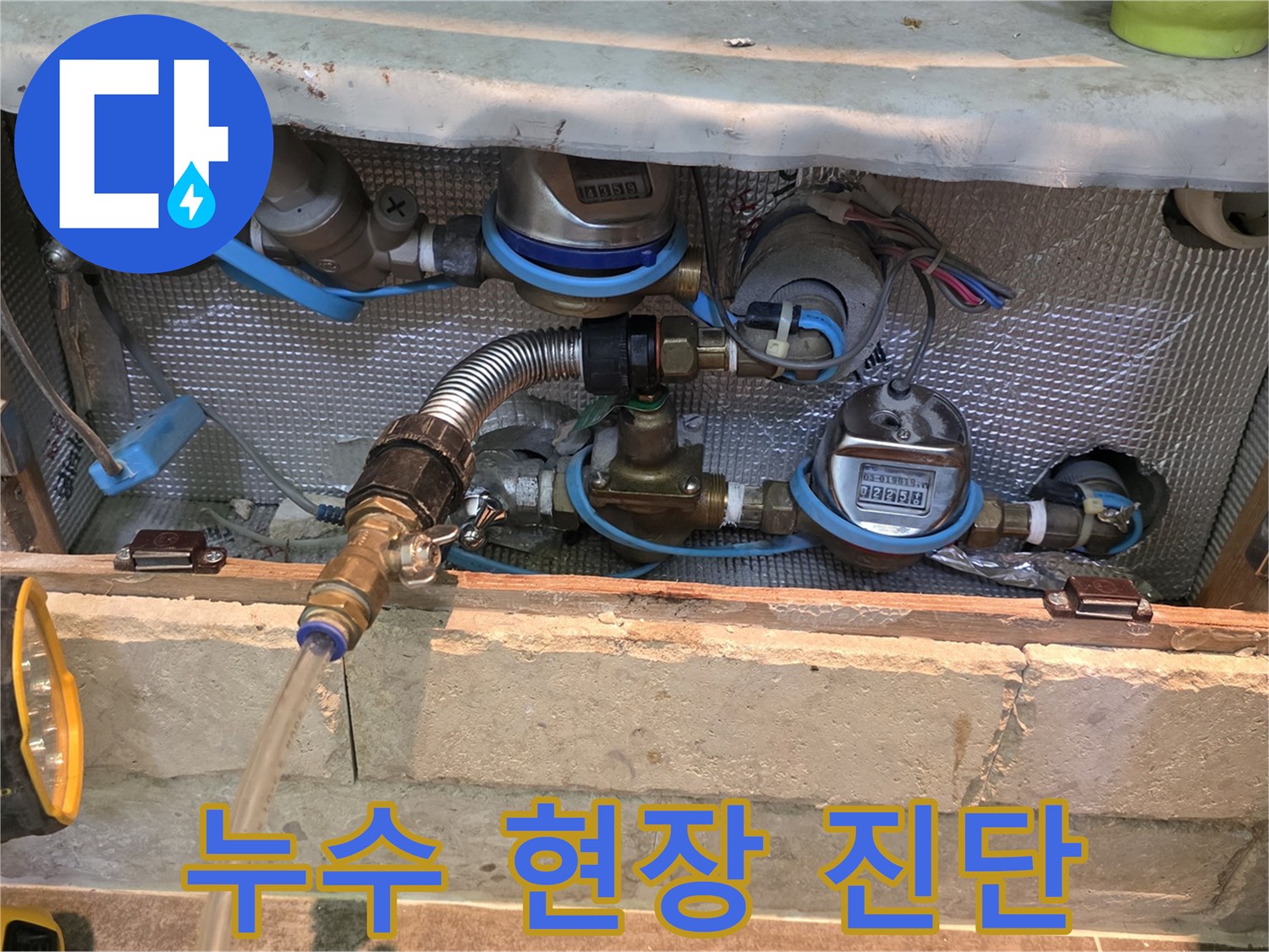 누수 진단을 위해 배관에 연결된 유연한 금속 호스와 투명한 배출 호스-정확한 누수 위치를 파악하기 위한 전문적인 장비 사용 모습입니다.