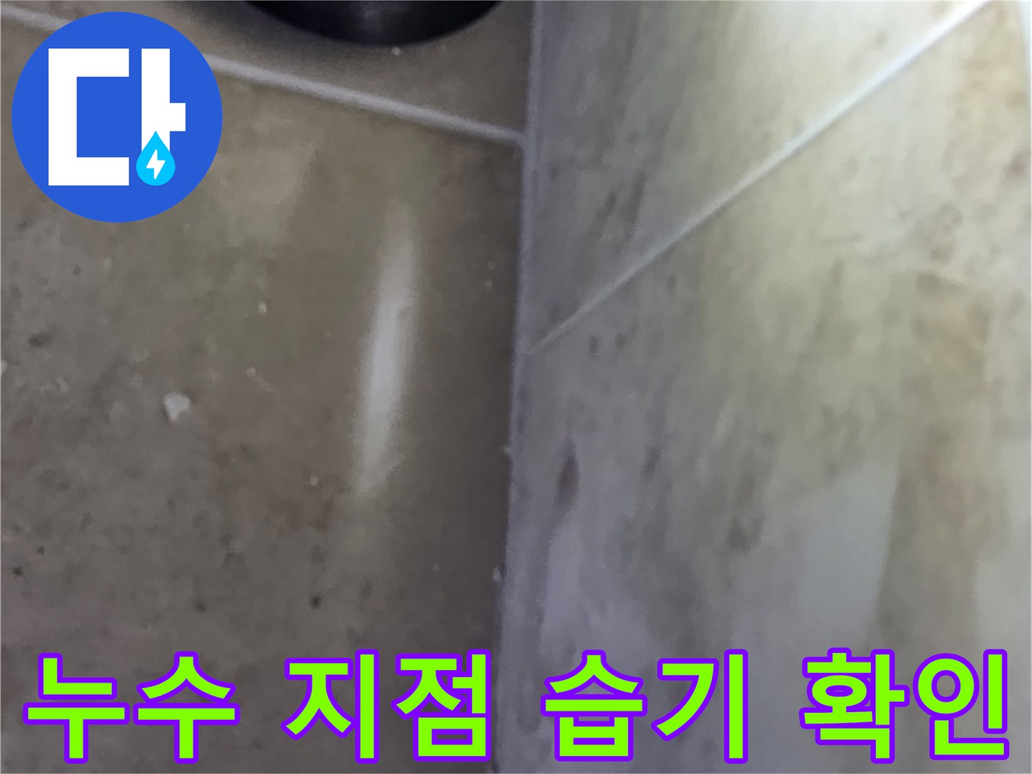 타일 바닥과 벽면의 접합부에서-습기가 감지되어 누수 지점을 파악하는 모습
