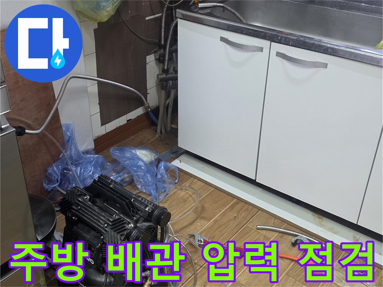 주방 싱크대 하부장 아래에서 진행 중인 배관 공압 테스트 현장입니다.