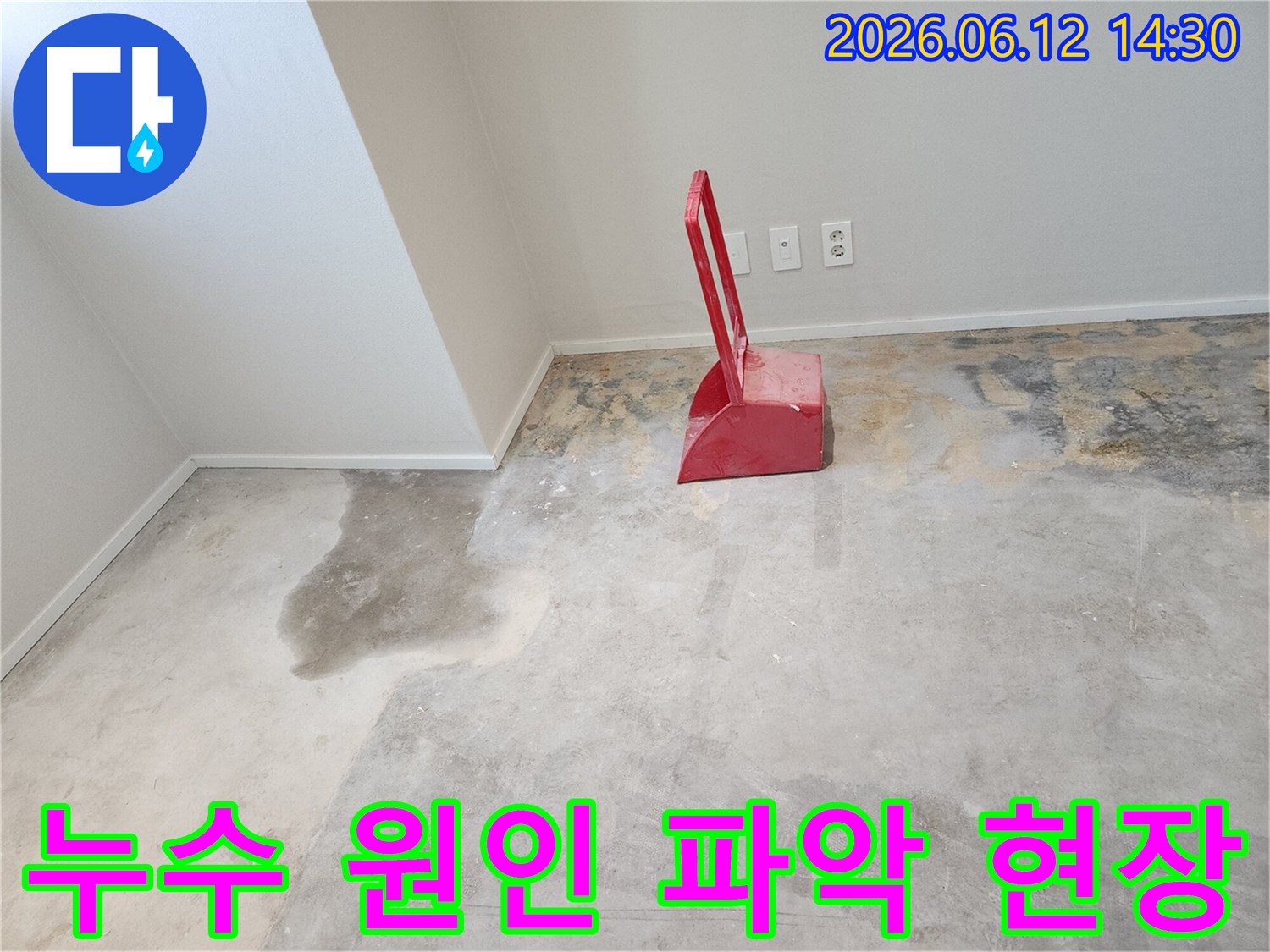 누수-현장에서-콘크리트-바닥에-젖은-부분과-빨간색-청소-도구가-함께-찍힌-사진