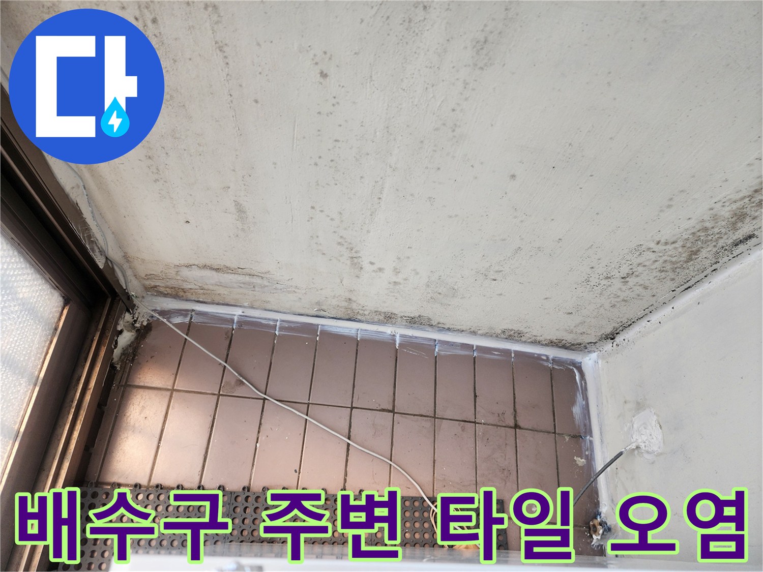 베란다 바닥 타일과 벽면 경계 부위의 오염된 상태를 촬영한 사진입니다.