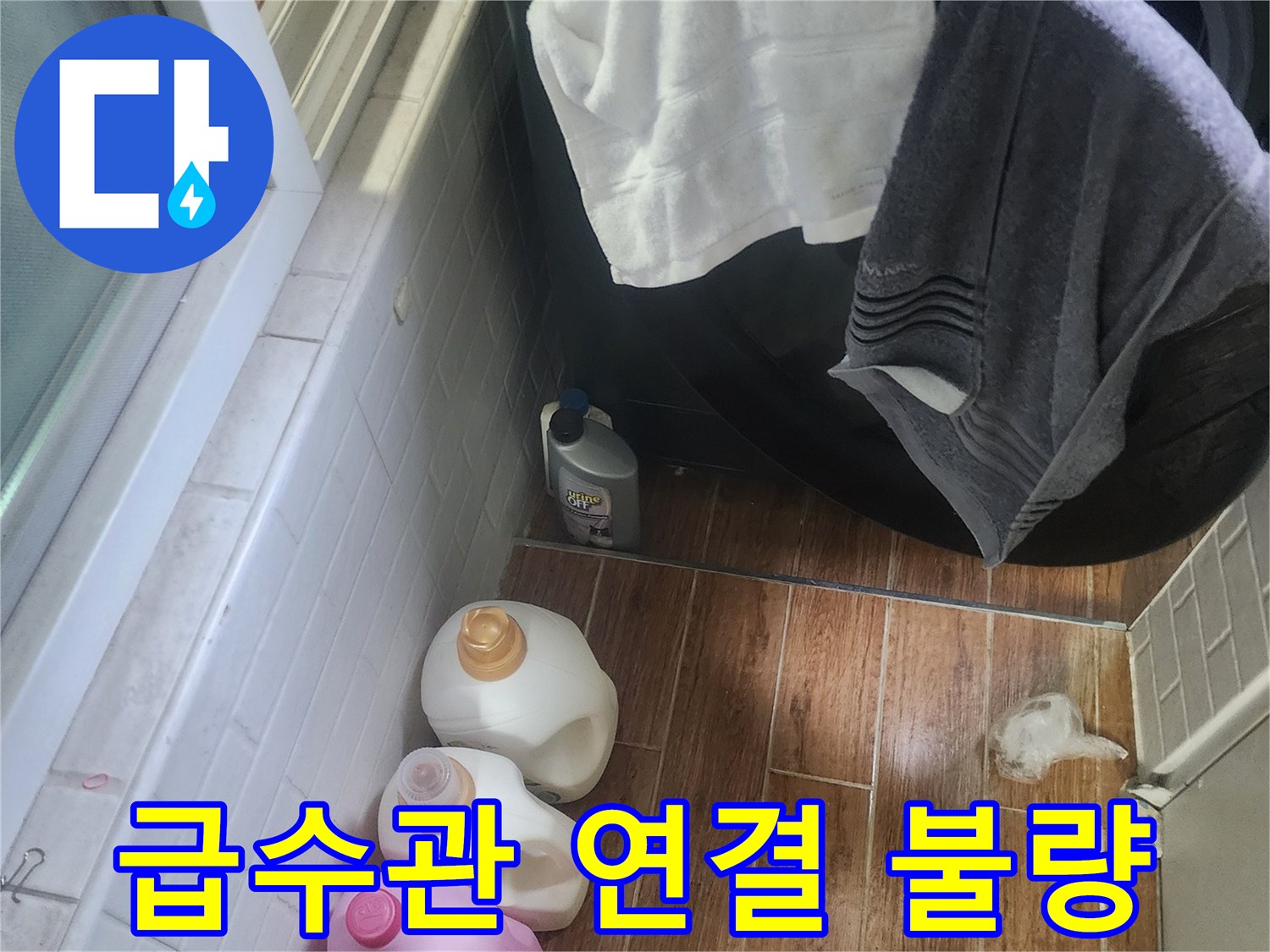 세탁기 옆 바닥에 물이 고여 있고-세제 용기들이 놓여 있는 누수 현장입니다.
